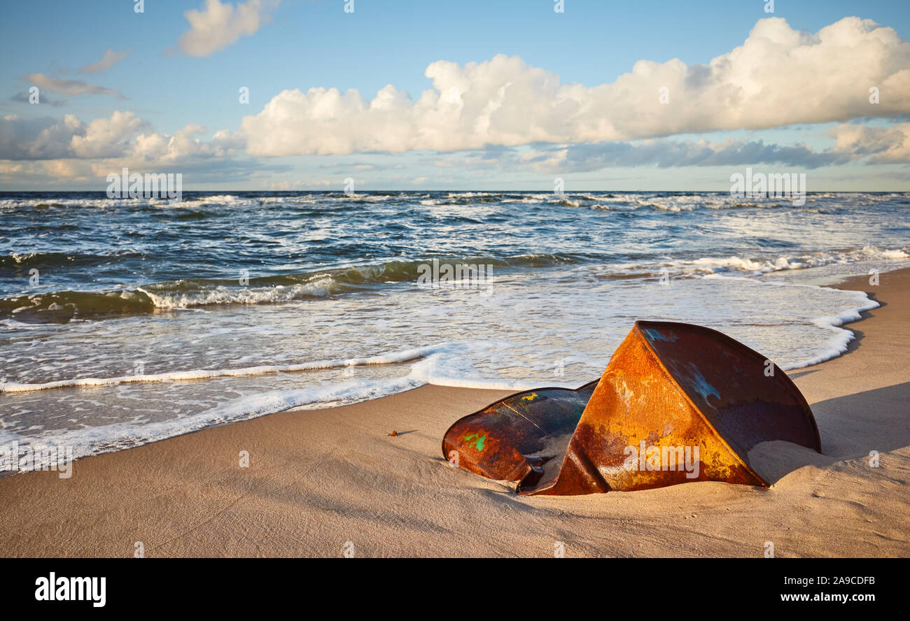 Baril rouillé sur une plage au coucher du soleil, la pollution de l'environnement concept. Banque D'Images