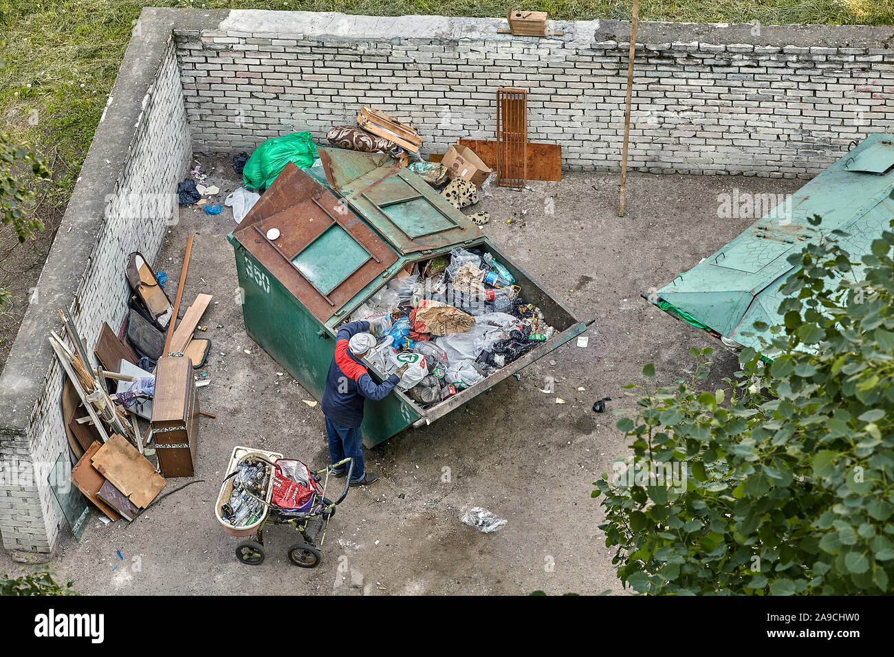 Saint-pétersbourg, Russie - 9 juin 2019 : les pauvres sont à la recherche pour les produits recyclables dans la poubelle pour la vente. Trop plein de bac à déchets Collecte des déchets mixtes. Banque D'Images