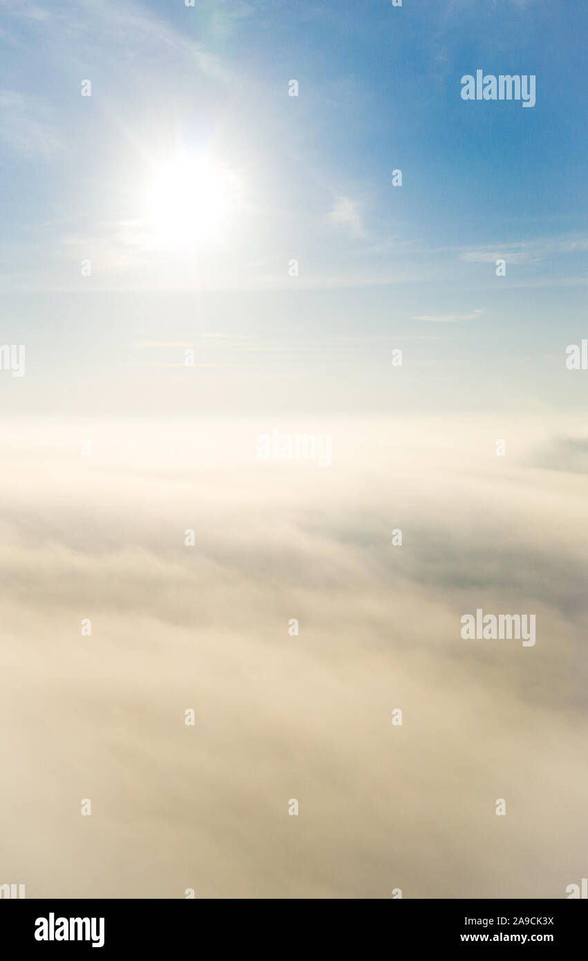 Photo aérienne au-dessus du brouillard ou des nuages blancs avec soleil. Beau lever de soleil ciel nuageux à partir de la vue aérienne. Les nuages au-dessus de la fenêtre de l'avion ou drone Banque D'Images
