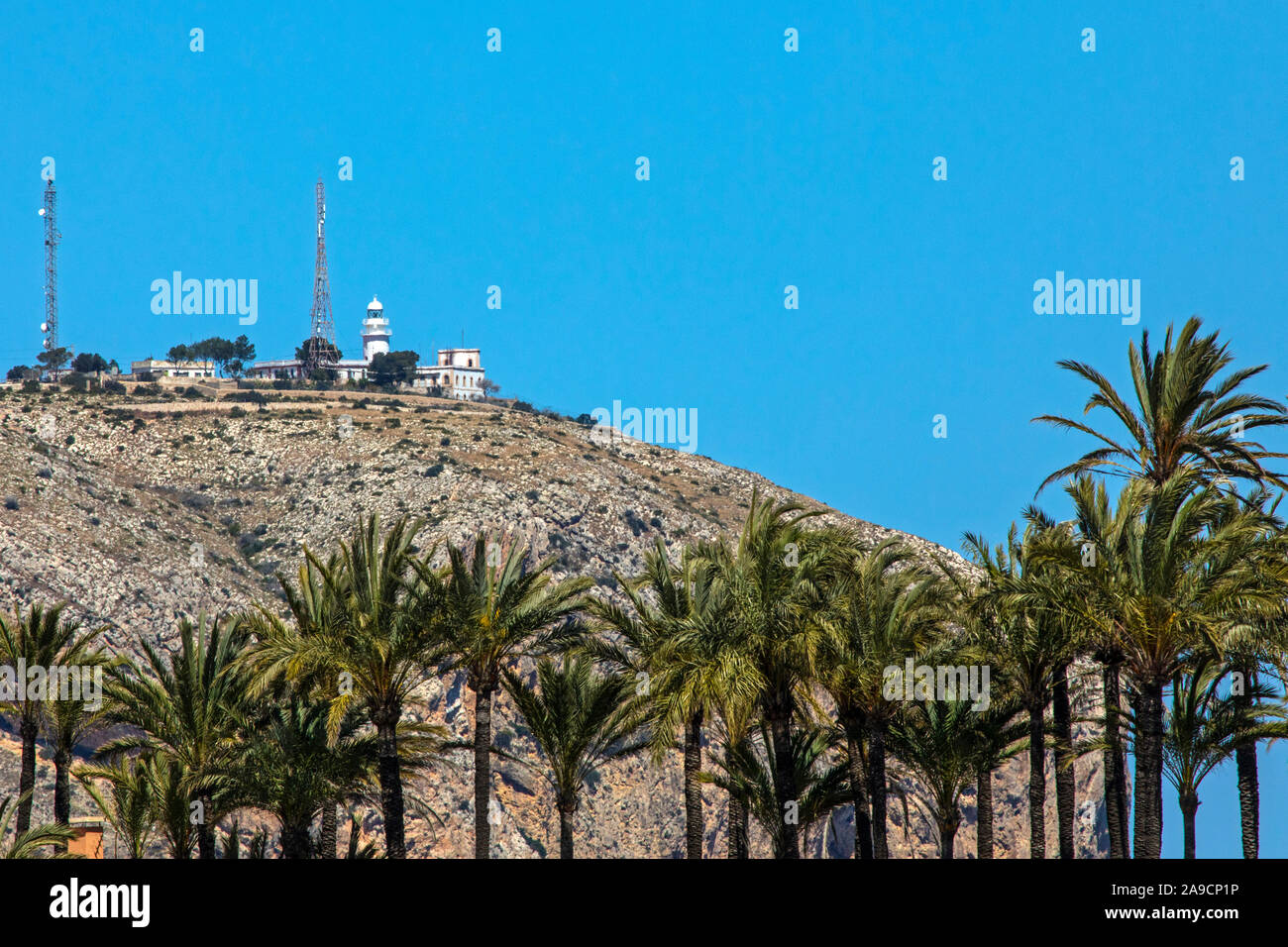 Une vue sur les palmiers de la plage et les falaises du Cap de Sant Antoni à Javea, Espagne. Banque D'Images