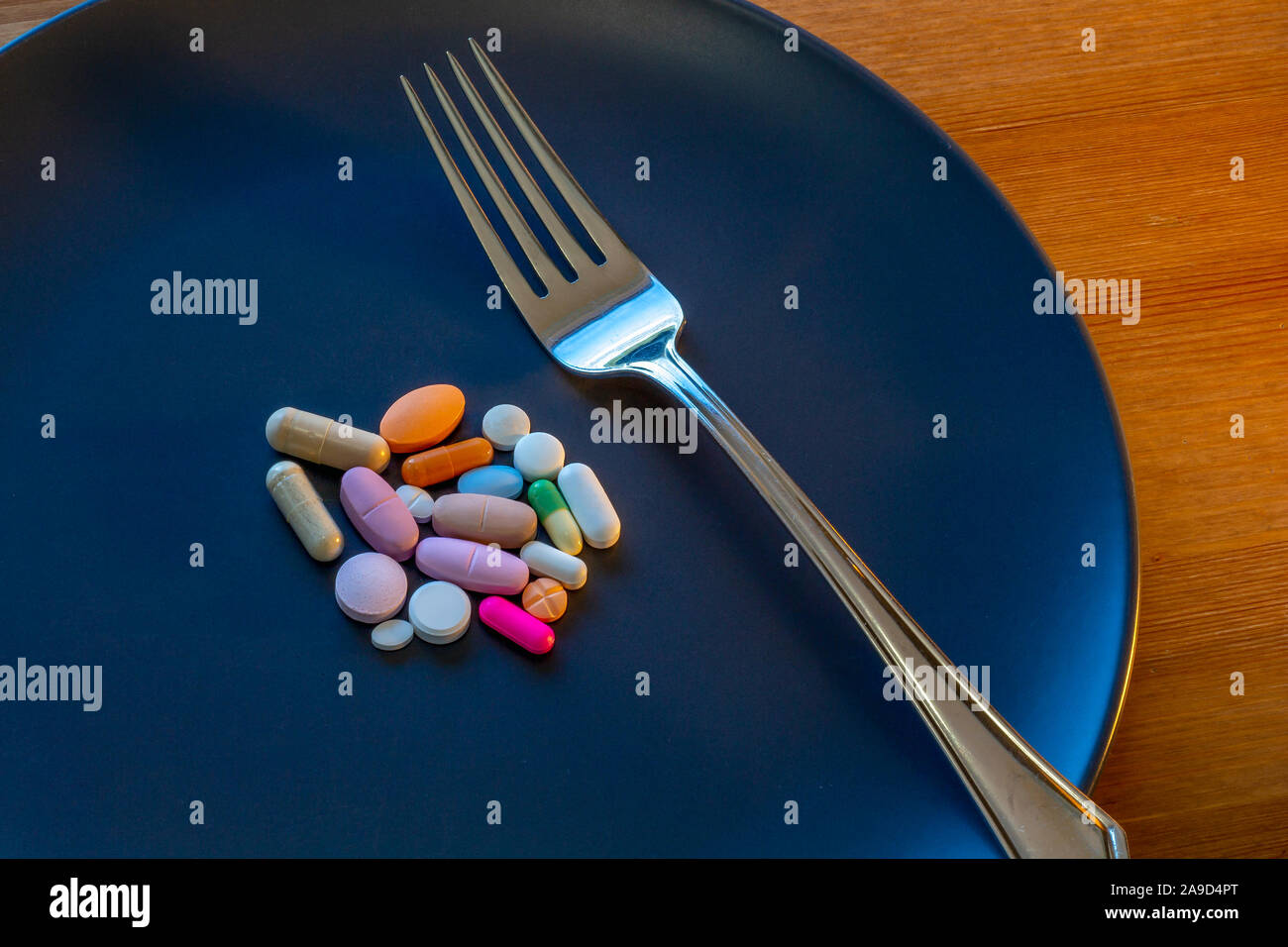 Une plaque gris foncé a un assortiment de pilules à son centre, dont les médicaments sur ordonnance, les médicaments en vente libre, les vitamines et autres suppléments. Banque D'Images