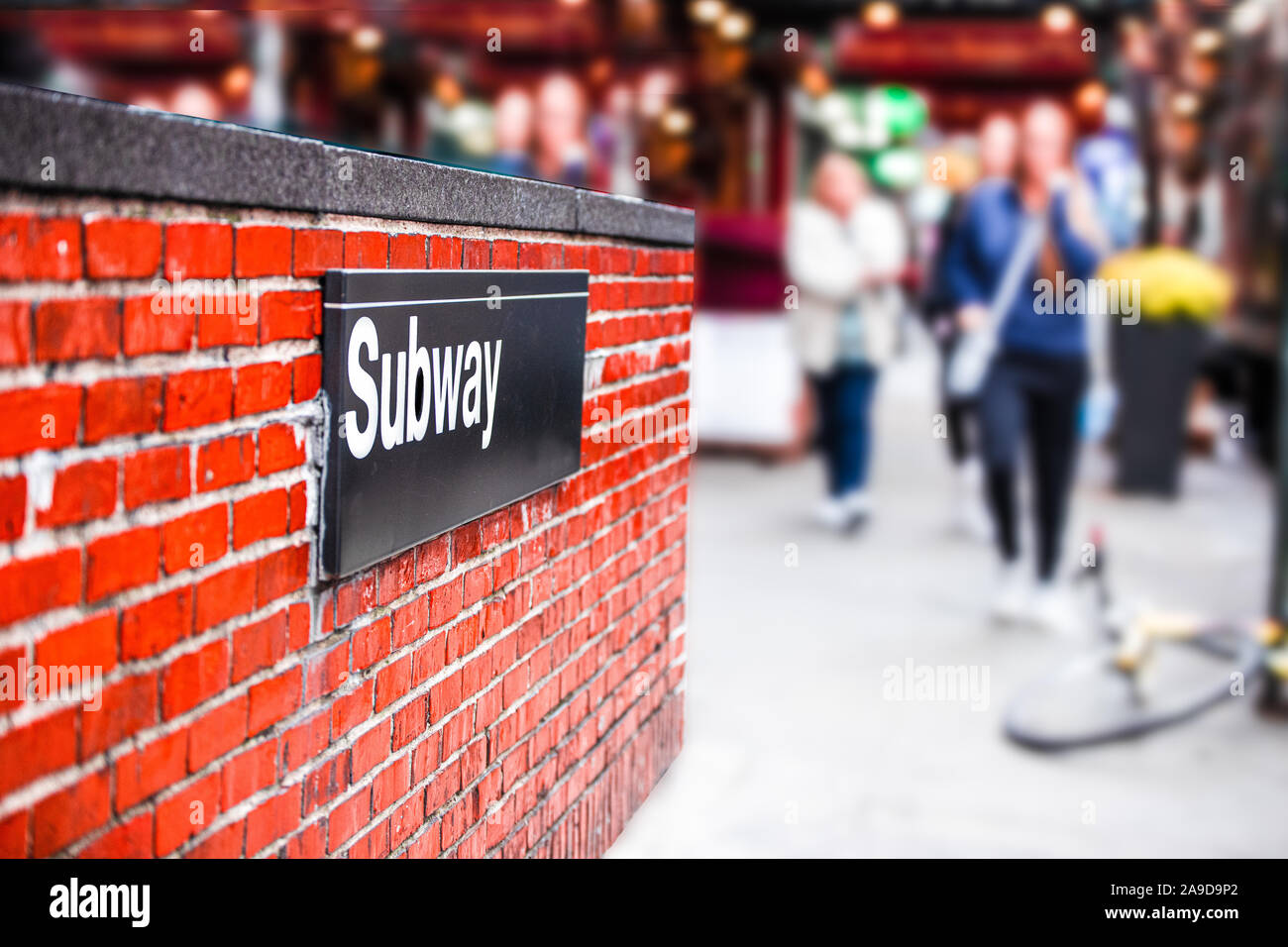 New York City coin de rue avec entrée du métro signe sur mur de briques et de brouiller d'hommes marcher en arrière-plan Banque D'Images