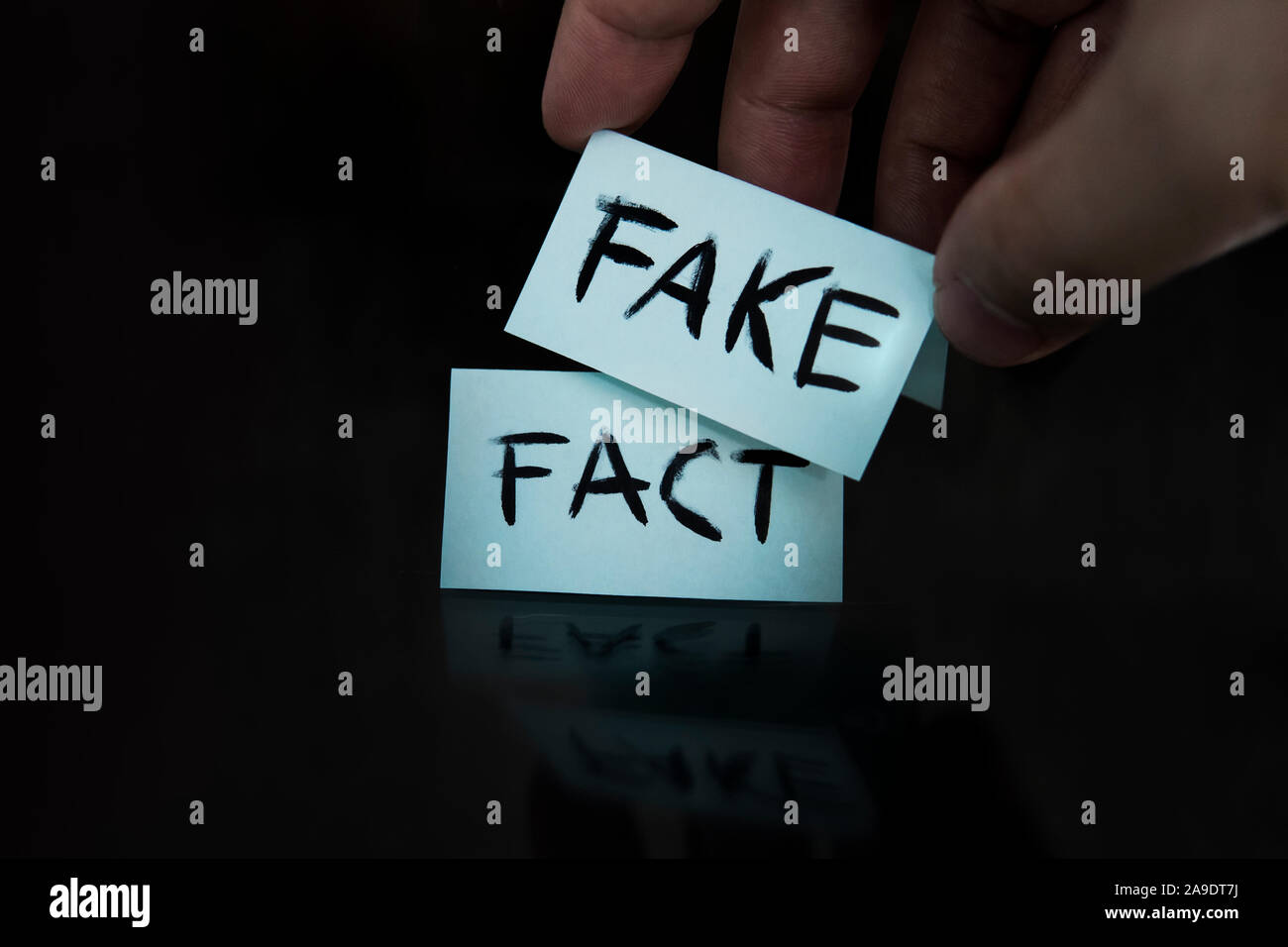 Substitution des concepts. Le fait est remplacé par un faux. un homme change le signe avec les mots fait sur les faux sur un fond noir. Banque D'Images