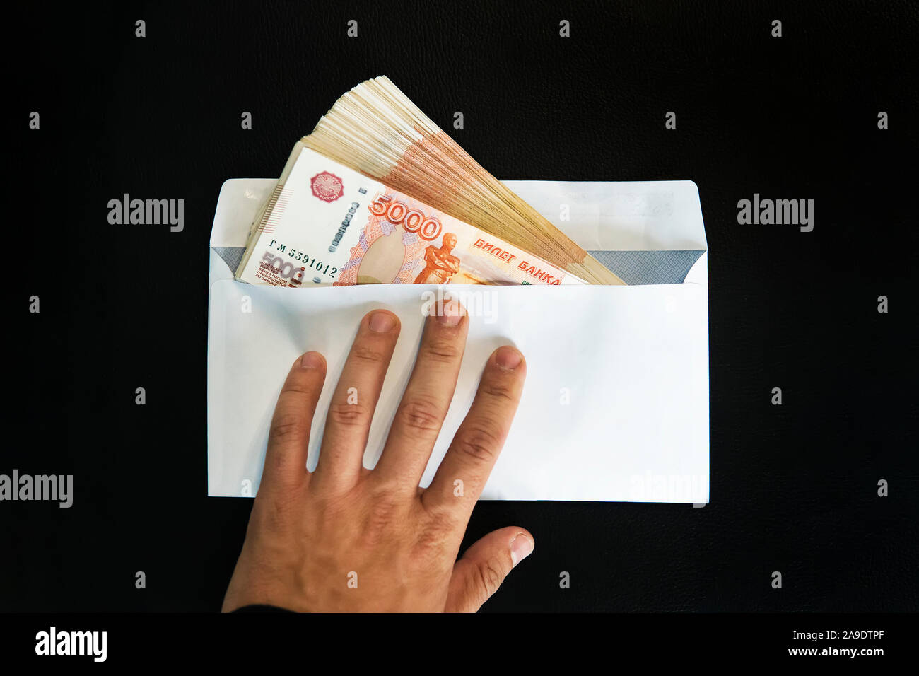 Grosses coupures de 5000 roubles dans une enveloppe blanche. Un homme part détient une enveloppe avec de l'argent. Le concept de corruption, le cash flow de trésorerie. Banque D'Images