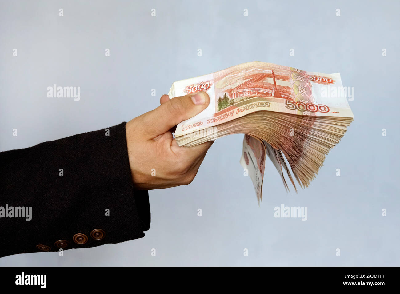 La main avec roubles russes sur un fond bleu, les projets de cinq mille roubles, de l'argent dans la main du ventilateur. Une grande somme d'argent avec un million de roubles pour la main o Banque D'Images