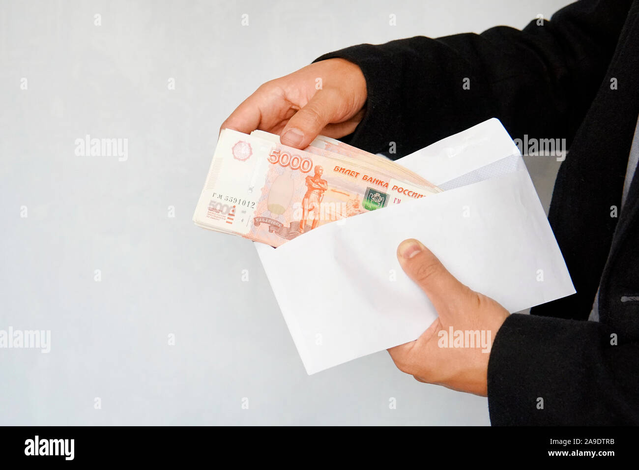 Grosses coupures de 5000 roubles dans une enveloppe blanche. Un homme part détient une enveloppe avec de l'argent. La notion de corruption et de main d'hommes rec. Banque D'Images