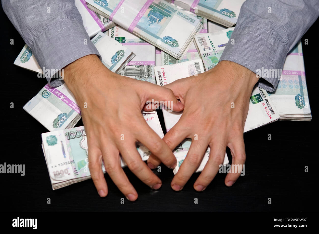 Les mains des hommes pour atteindre une liasse d'argent. Un million de roubles sur le tableau noir. Le concept de la richesse, le succès, la cupidité et la corruption, la soif de l'argent Banque D'Images