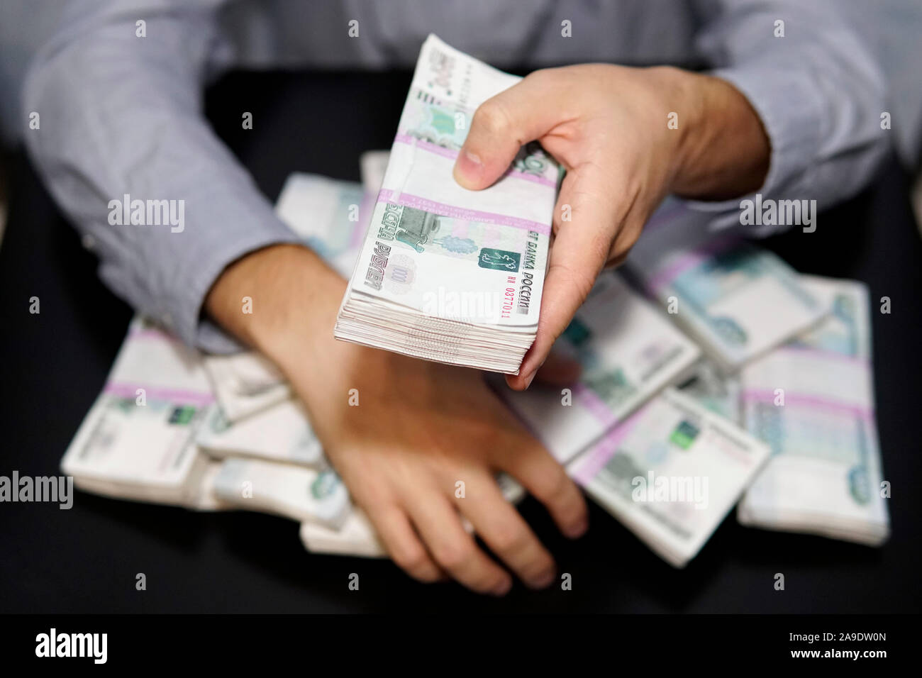 Les mains des hommes pour atteindre une liasse d'argent. Un million de roubles sur le tableau noir. Le concept de la richesse, le succès, la cupidité et la corruption, la soif de mone Banque D'Images