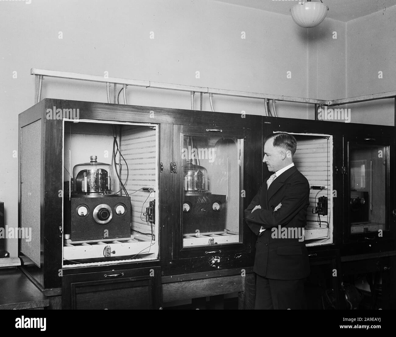 Homme avec un groupe de 100 kHz oscillateurs à cristal de quartz qui a servi comme le U.S. National fréquence primaire standard en 1929 ca. 1930 Banque D'Images