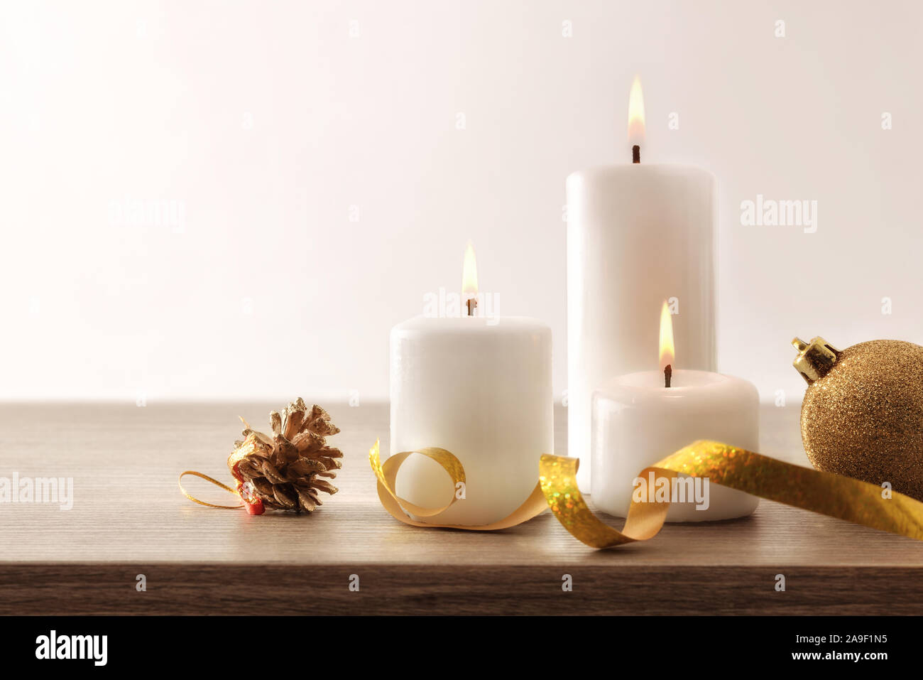 Composition de Noël Simple avec trois bougies allumées et éléments de Noël sur table en bois et fond isolé. Vue de face. Composition horizontale Banque D'Images