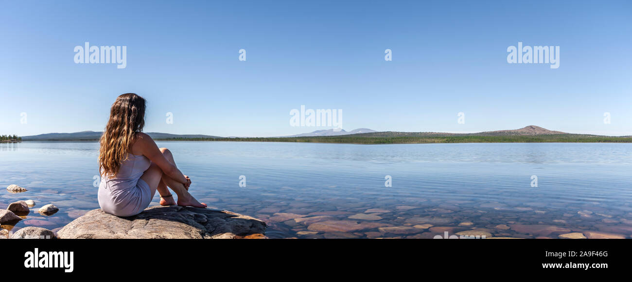 La femme est assise sur la rive Banque D'Images