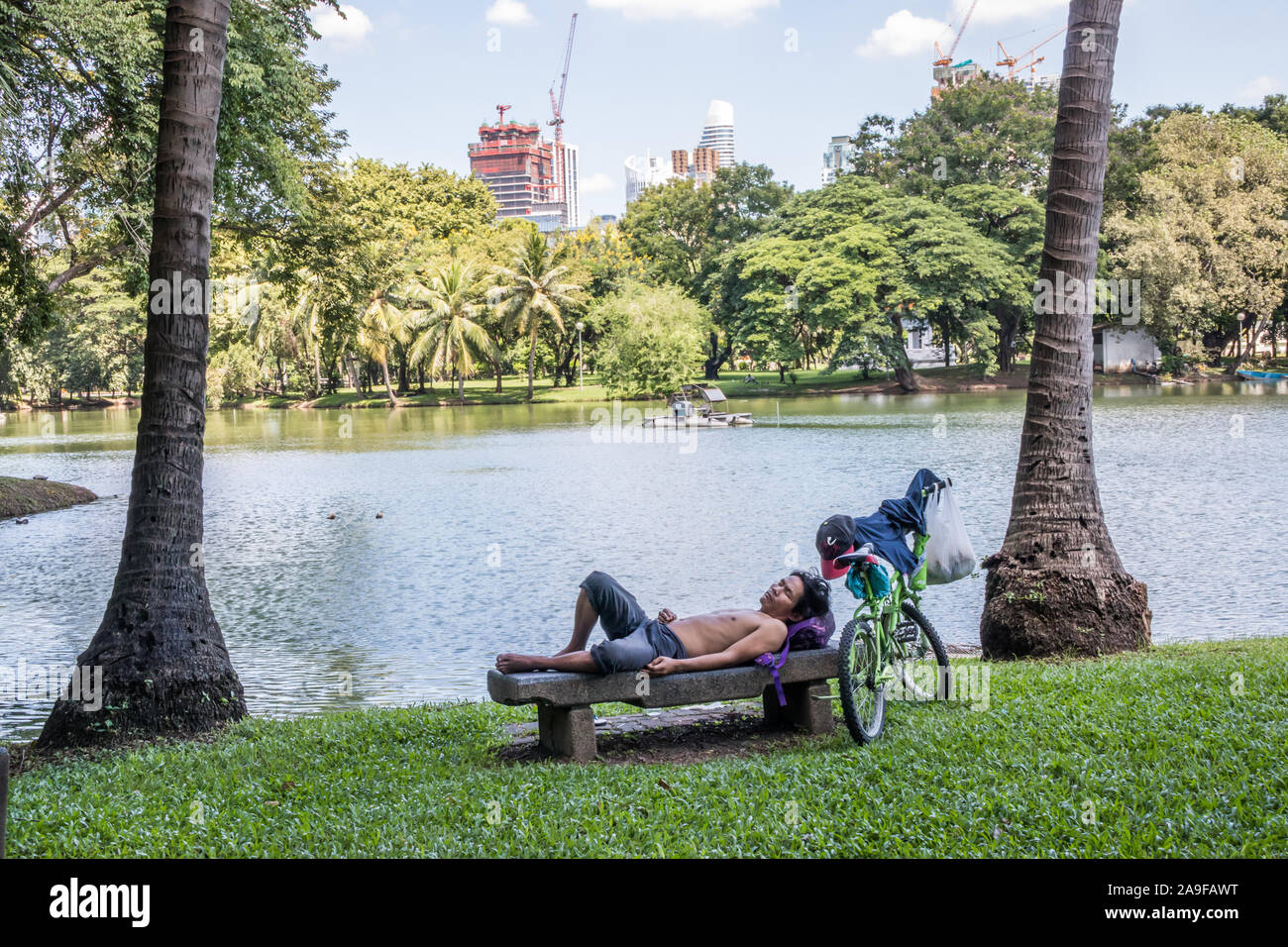 Bangkok, Thaïlande - 27 septembre 2018 : l'homme avec le vélo prend un repos par le Parc Lumphini lake. Le parc se trouve dans le centre de la ville. Banque D'Images