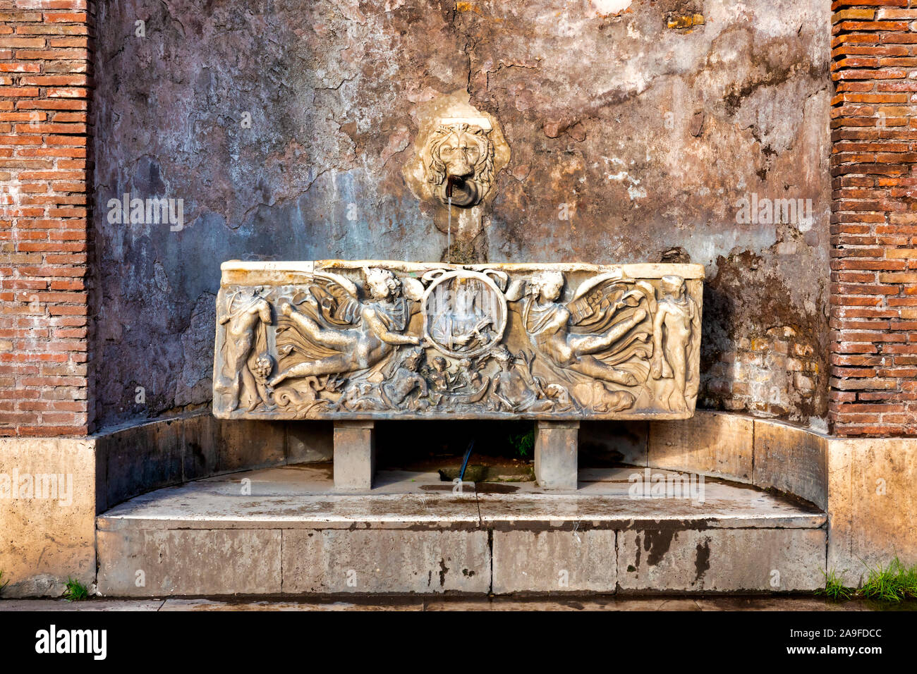Fontaine composée d'une tête de lion et un ancien sarcophage romain sur la Piazza del Colosseo, Rome Italie Banque D'Images
