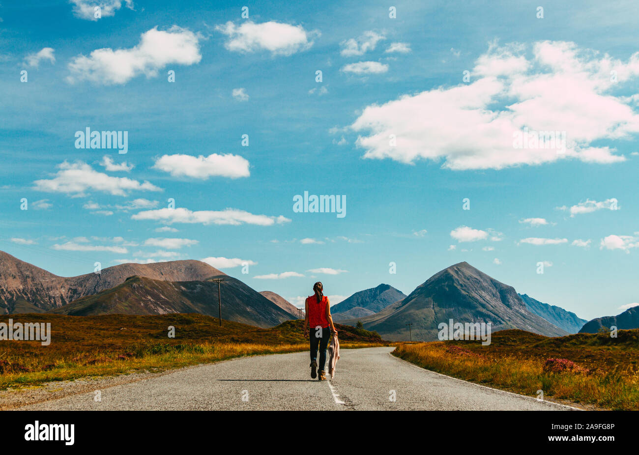 Une femme marche sur une route de montagne dans les îles écossaises Banque D'Images