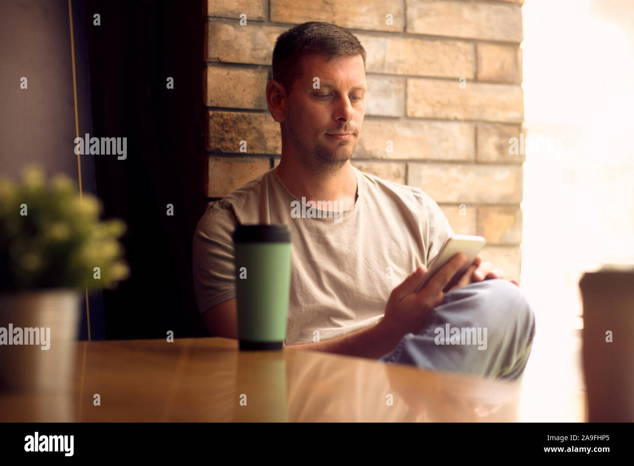 Jeune homme en utilisant smartphone dans cafe.Man relaxing in cafe et boire du café. Banque D'Images