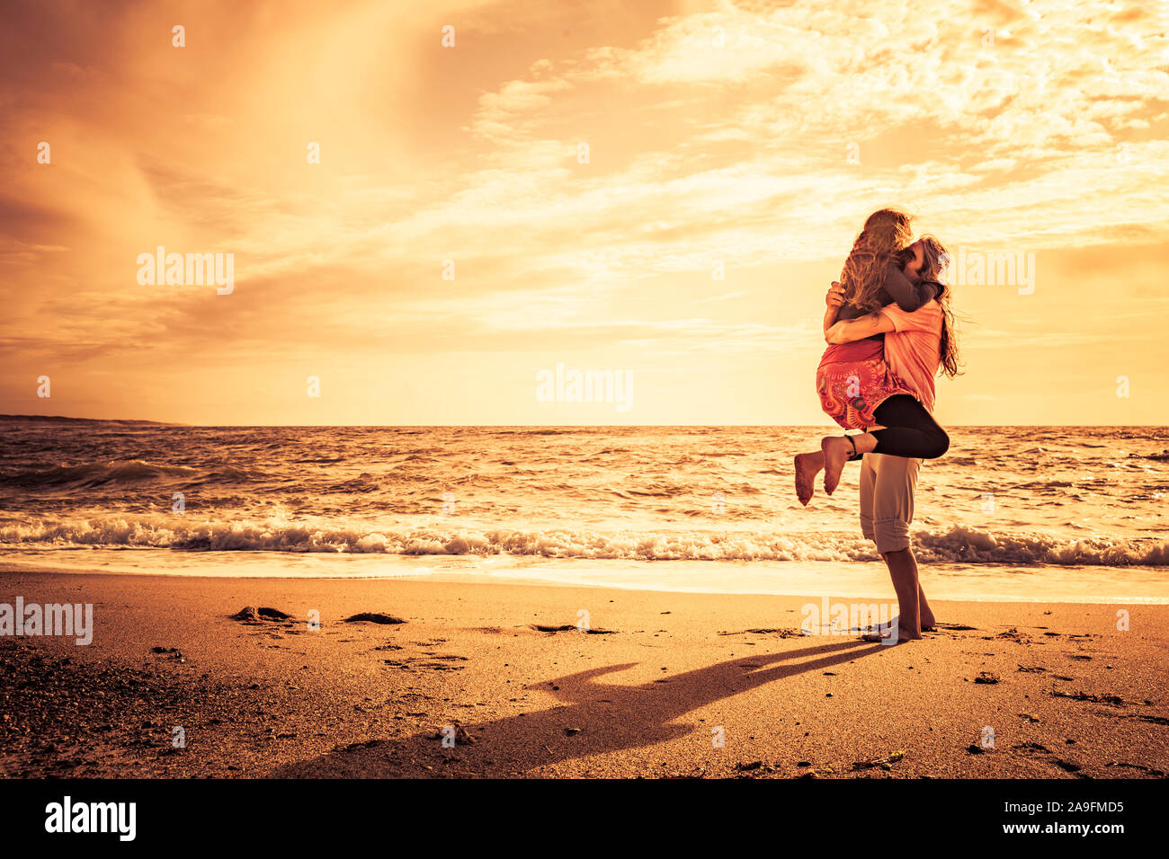 Couple heureux sur la plage au coucher du soleil Banque D'Images