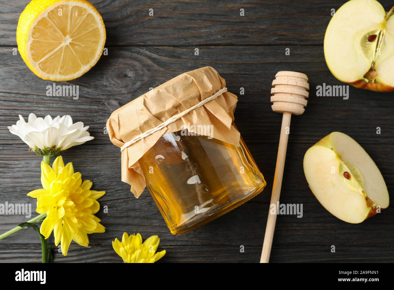 Balancier, pomme, citron, fleurs et pot de miel sur fond de bois, vue du dessus Banque D'Images