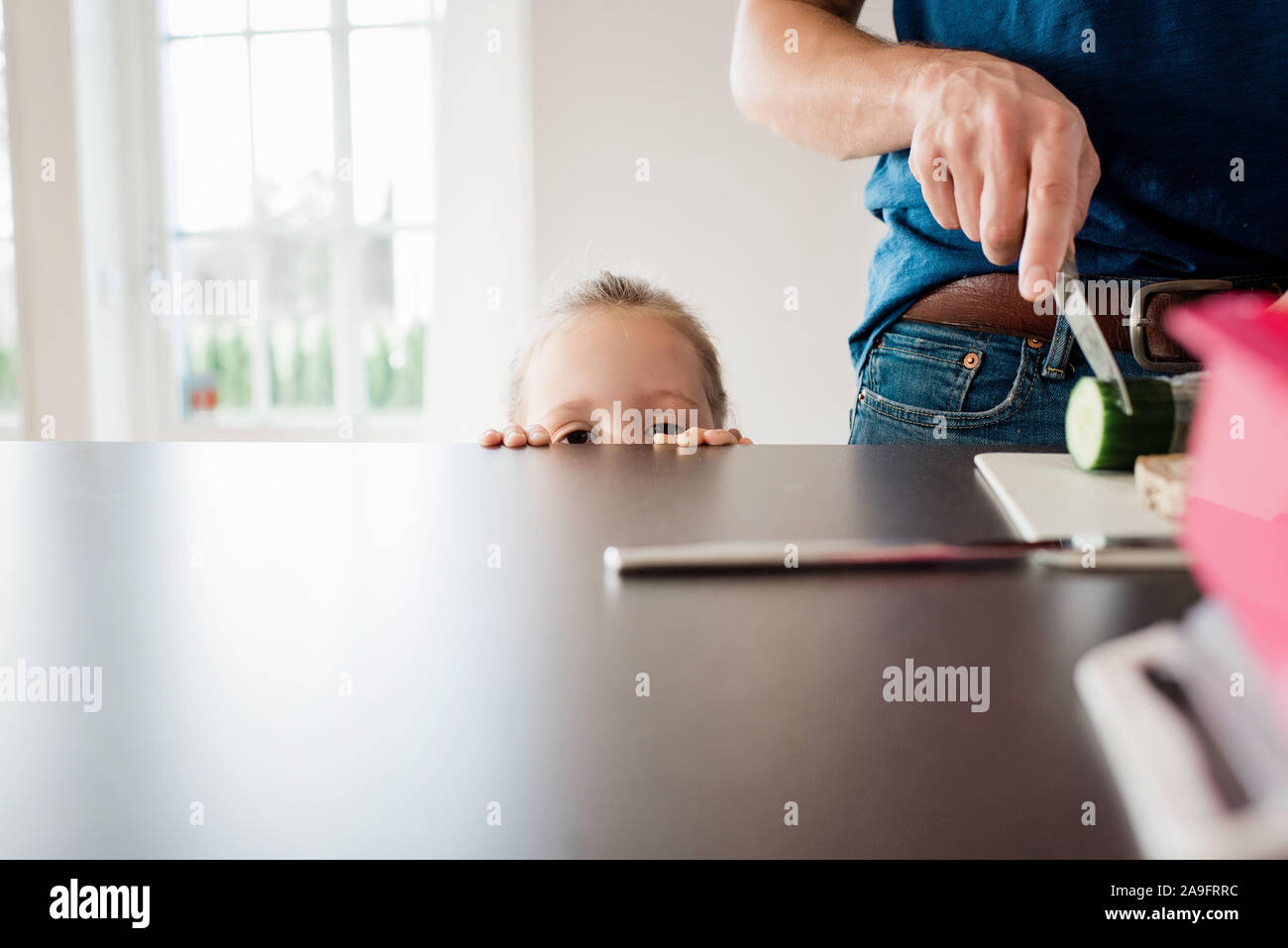 Père faisant un panier-repas pour l'école tandis que sa fille regarde Banque D'Images
