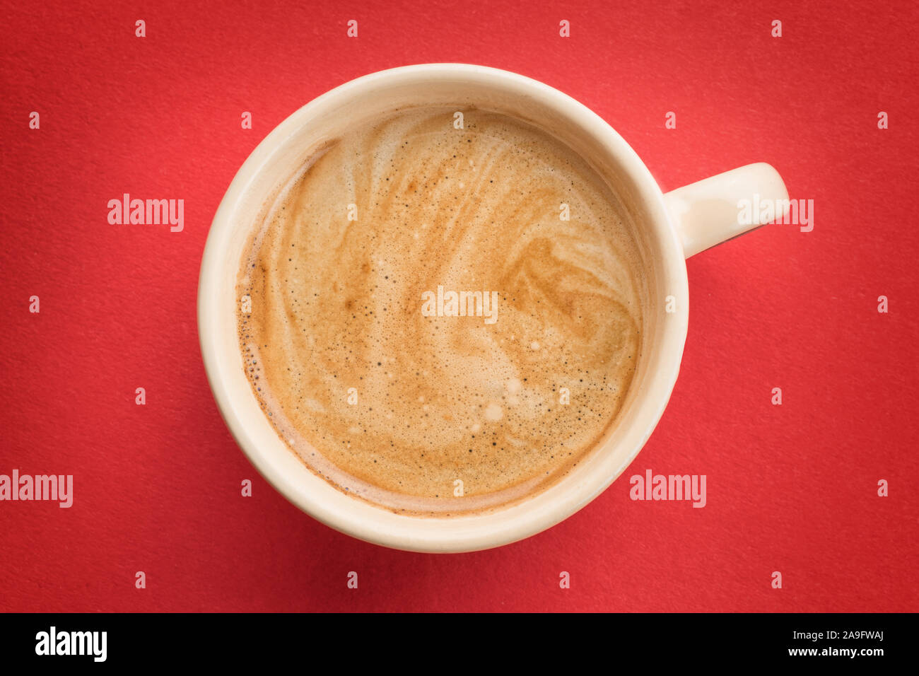 Tasse à café de couleur crème avec de la mousse sur fond rouge Vue de dessus Banque D'Images