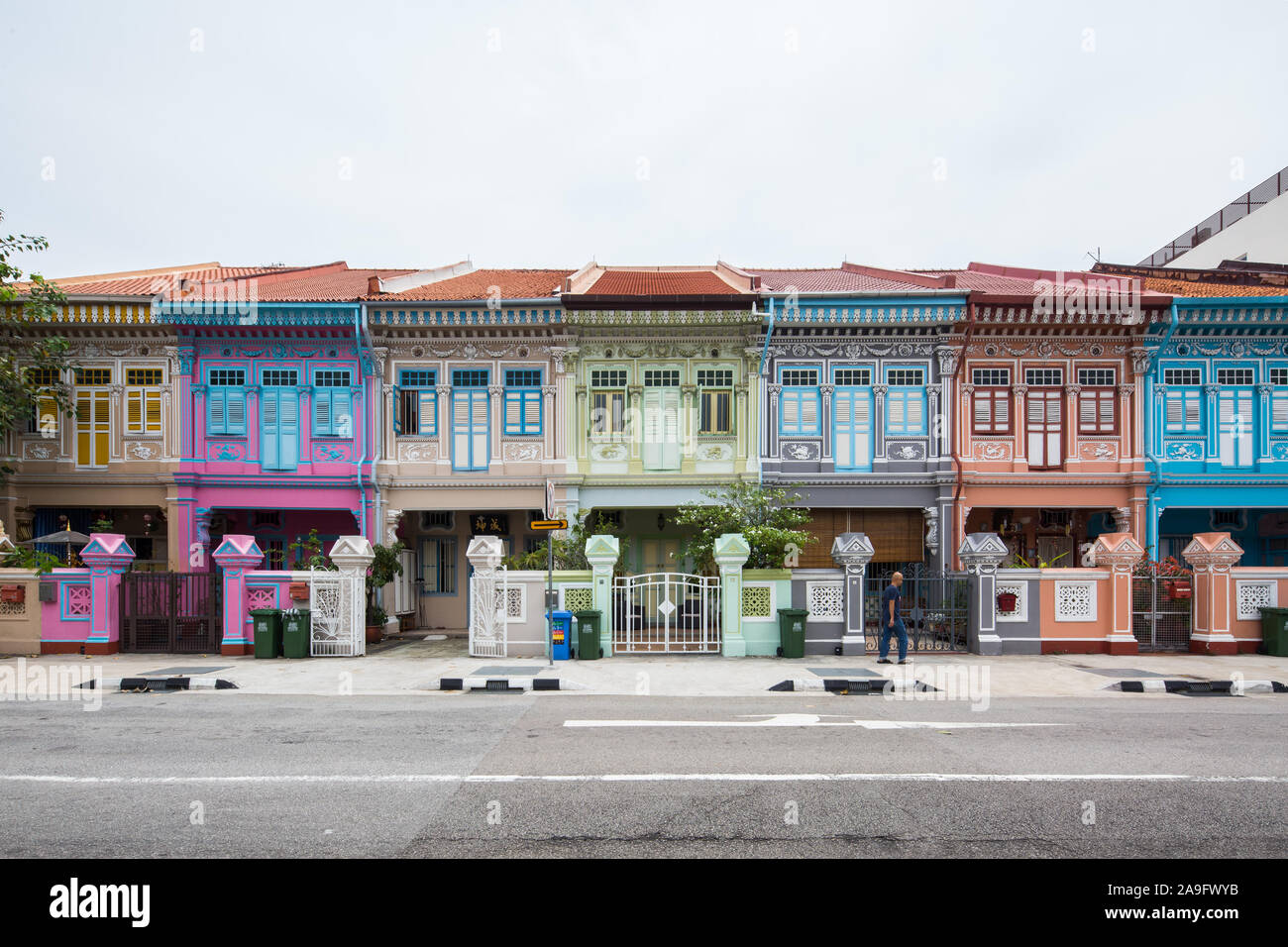Un homme traverse une rangée de vieux vestiaires historiques conservés de Peranakan dans le quartier de Joo Chiat. Singapour. Banque D'Images