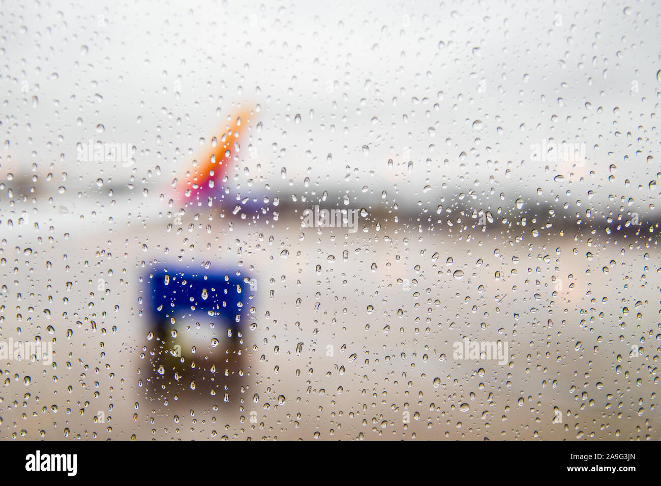 Regarder hors d'une fenêtre d'avion couverte d'eau chute avec l'aéroport floue. Banque D'Images