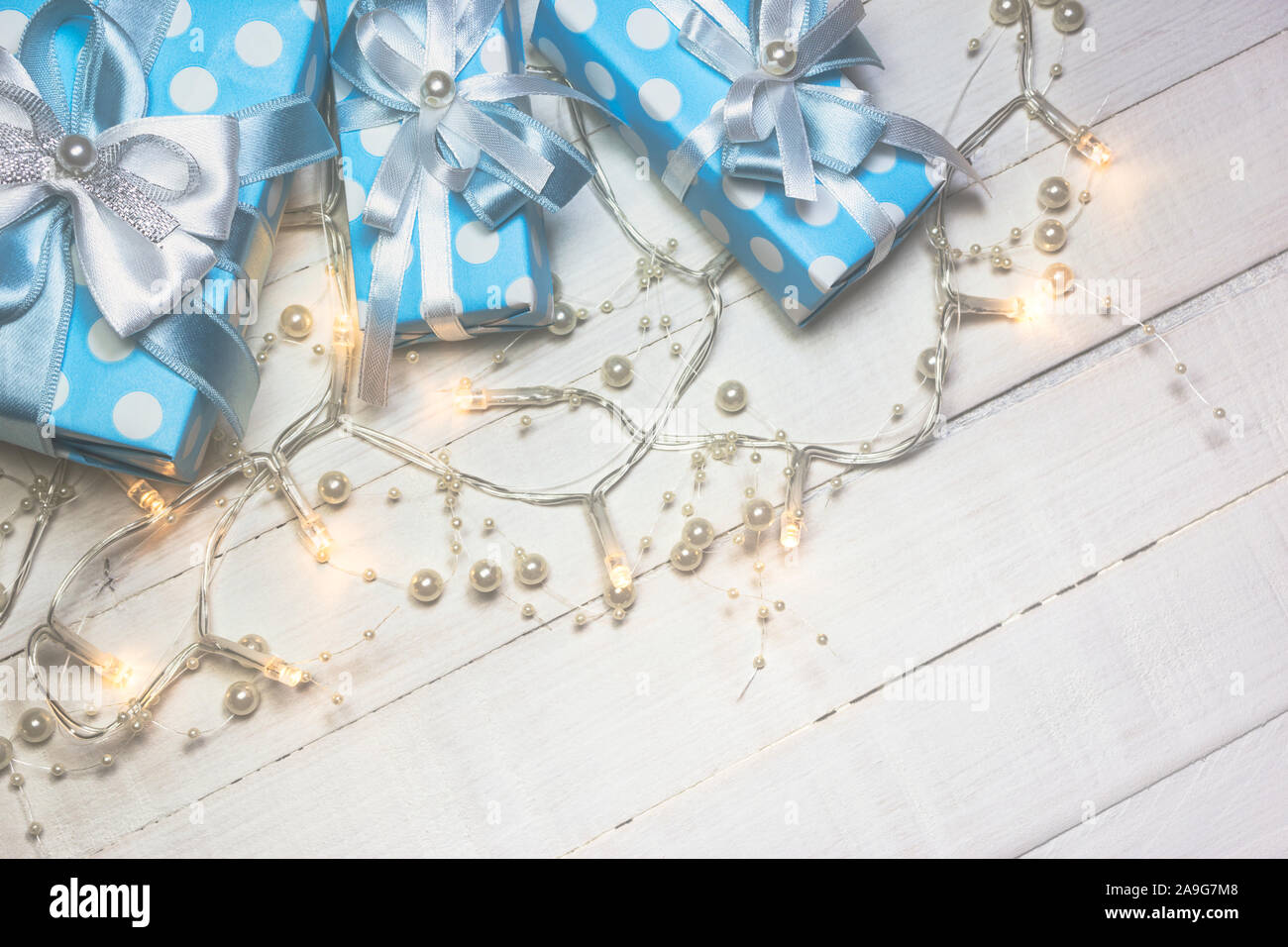 Vue de dessus de cadeaux bleu avec ruban blanc et bleu et décoré avec des lumières des perles sur fond en bois blanc, avec l'exemplaire de l'espace. Tons Vintage phot Banque D'Images