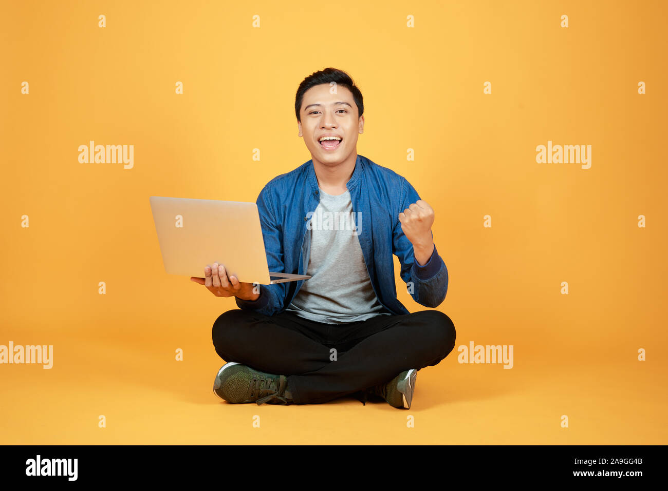 Heureux heureux Asian man holding laptop et élève son bras pour célébrer la réussite ou l'accomplissement. Banque D'Images