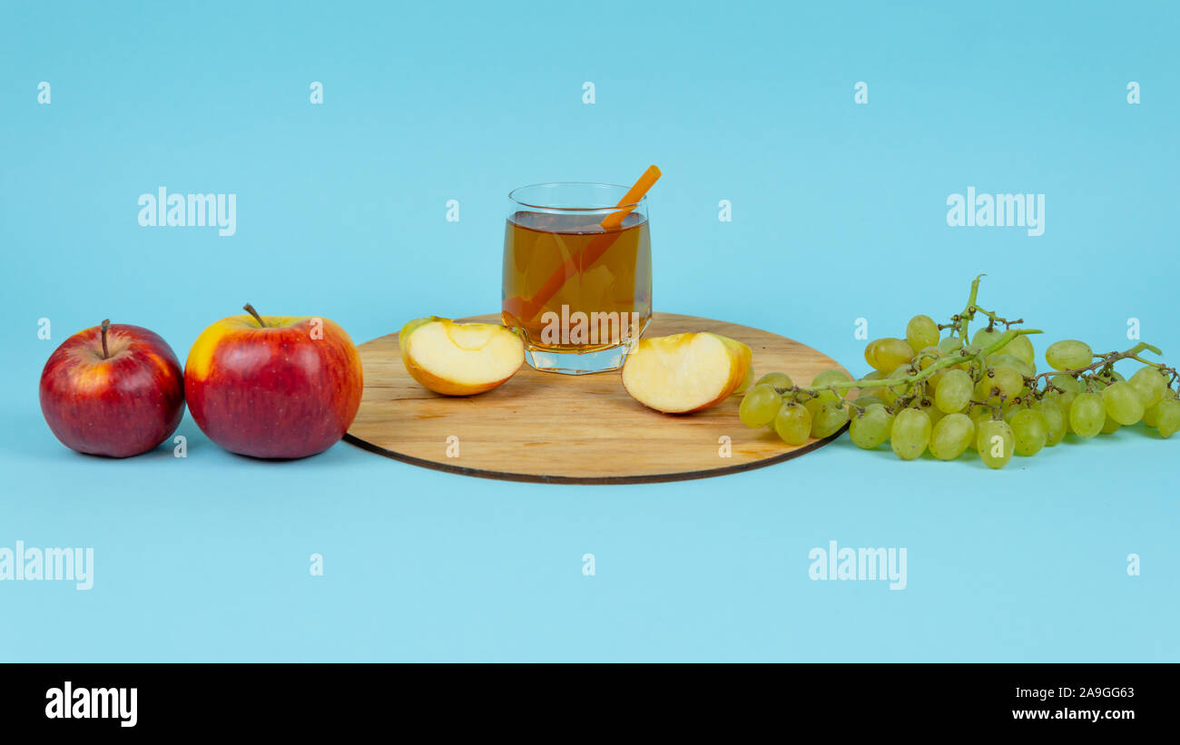 Verre de jus de raisin frais avec des pommes et sur fond bleu. Concept de l'alimentation, la saine alimentation et de l'aide pour le marketing Banque D'Images