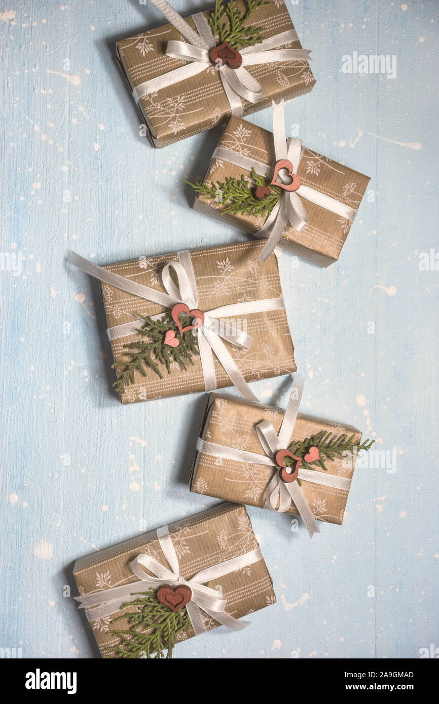 Cadeaux de Noël enveloppé dans du papier craft texturé sur fond bleu clair. Maison de vacances et de fête concept pour une carte postale ou par invitation. Vue de dessus avec le co Banque D'Images