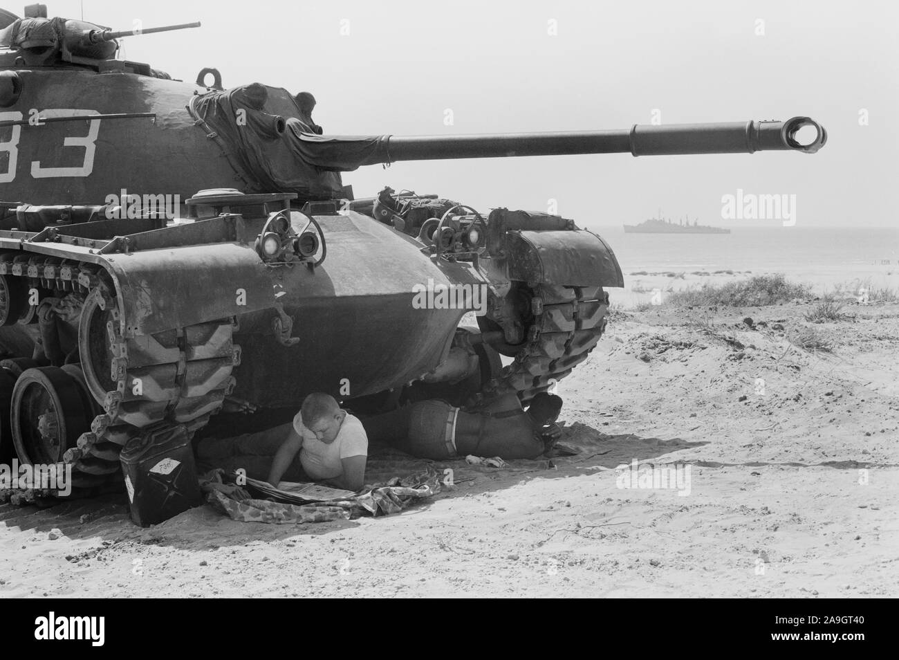 Soldat américain alors qu'un autre journal de lecture souder repose dans l'ombre sous un réservoir de marines américains à Beyrouth, Liban, photo de Thomas J. O'Halloran, Juillet 1958 Banque D'Images