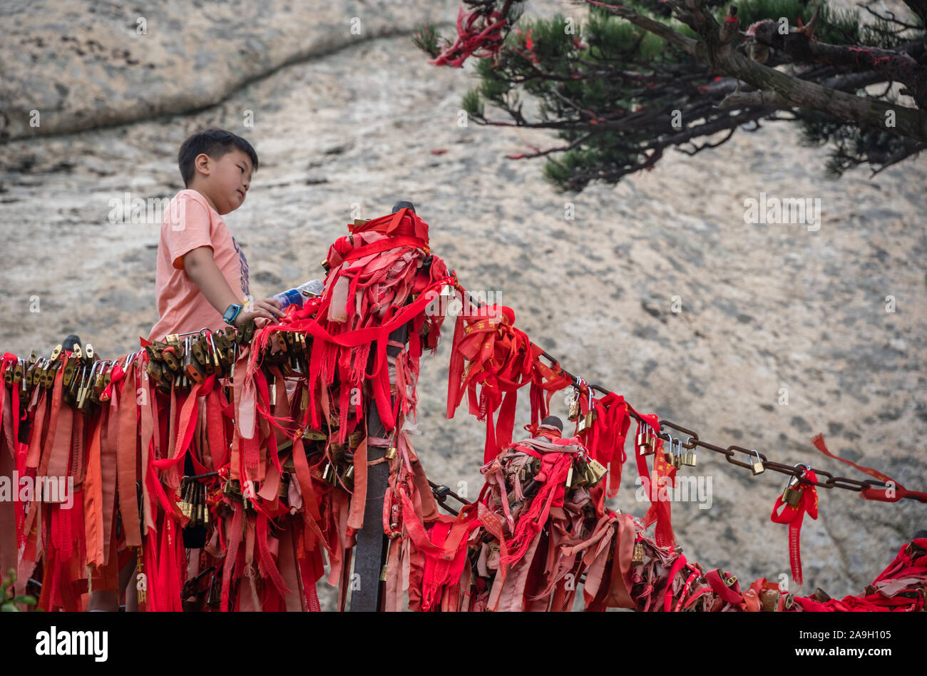 Huashan, Chine - Août 2019 : Chinese boy standing under petit arbre et poser pour des photos sur une crête étroite sur un sentier de montagne de l'Ouest à l'Afrique du P Banque D'Images