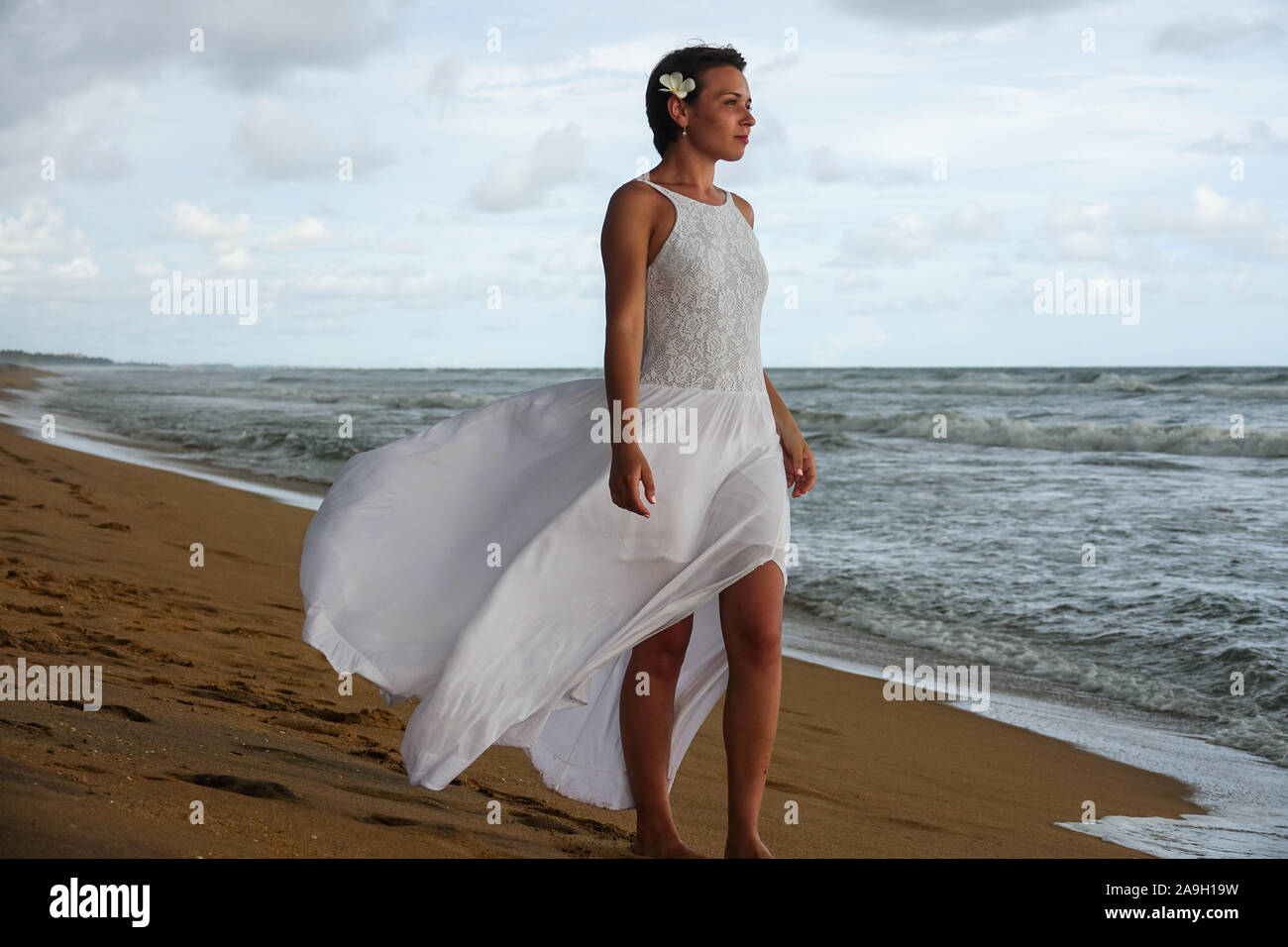 Jeune fille en robe blanche se réunit le coucher du soleil sur la plage de  l'océan tropical. Jeune fille cherche dans la distance Photo Stock - Alamy