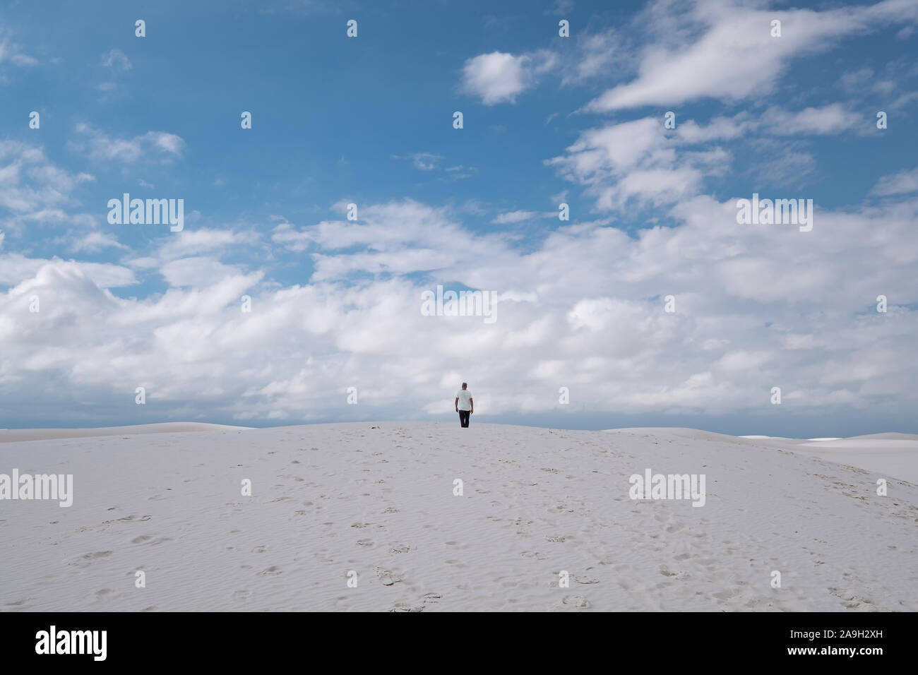 L'homme dans des vêtements décontractés au milieu de dunes de sable blanc contre le ciel bleu Banque D'Images