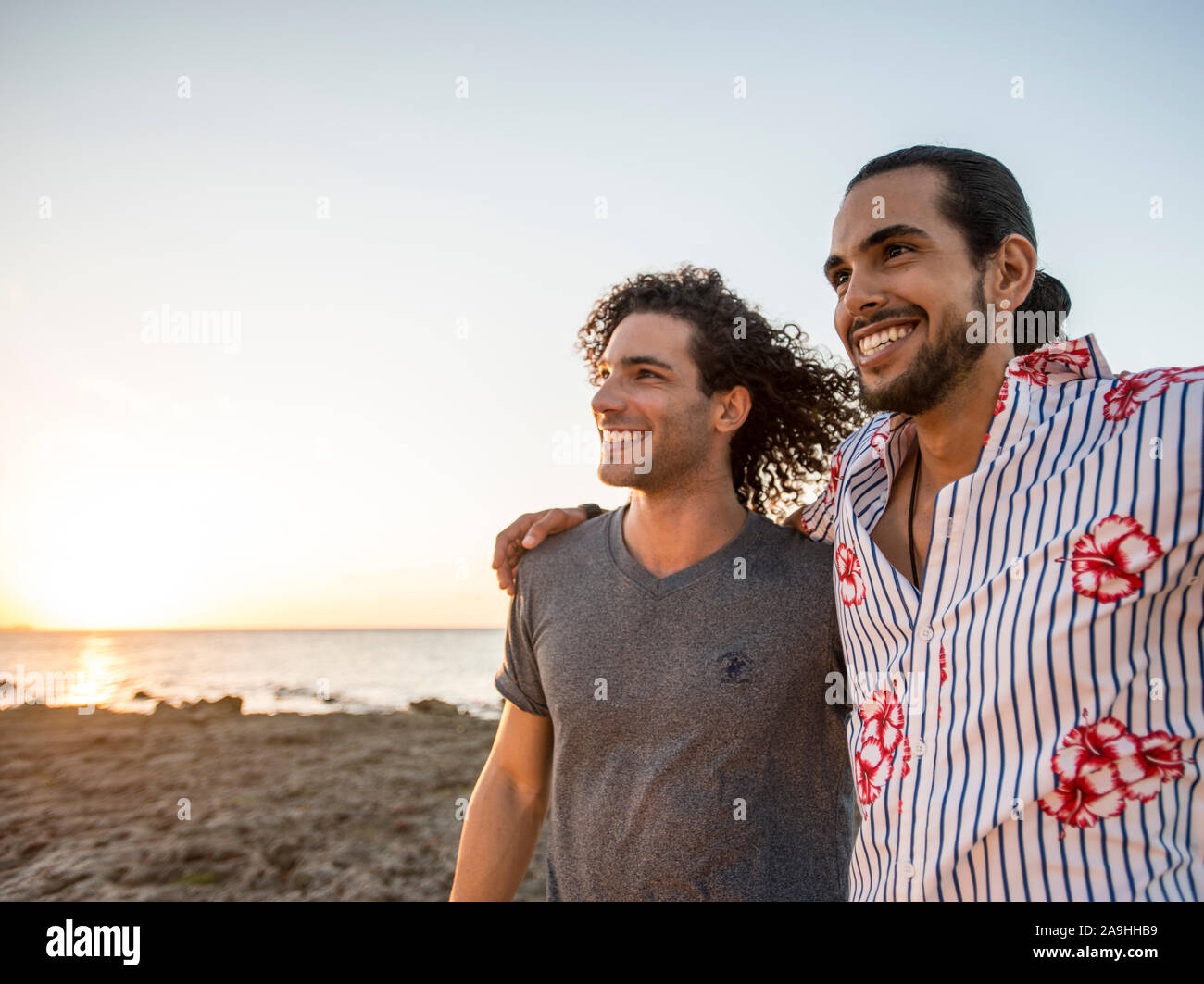 Deux amis marchant sur la plage pendant le coucher du soleil Banque D'Images