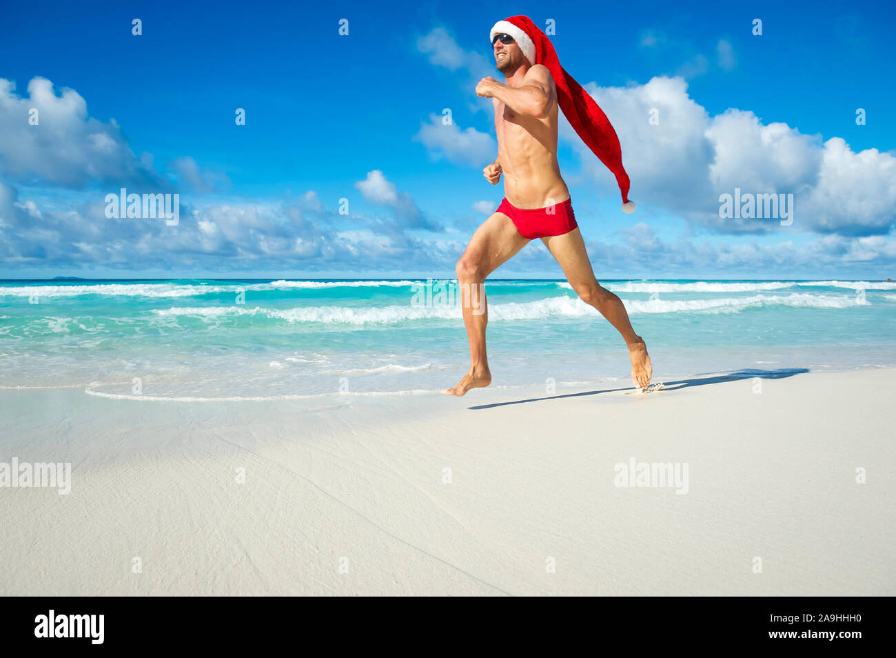 Mettre en place du père Noël avec de longues hat exécutant en rouge natation mémoires sur le rivage d'une plage tropicale Noël dans un régime de remise en forme Banque D'Images