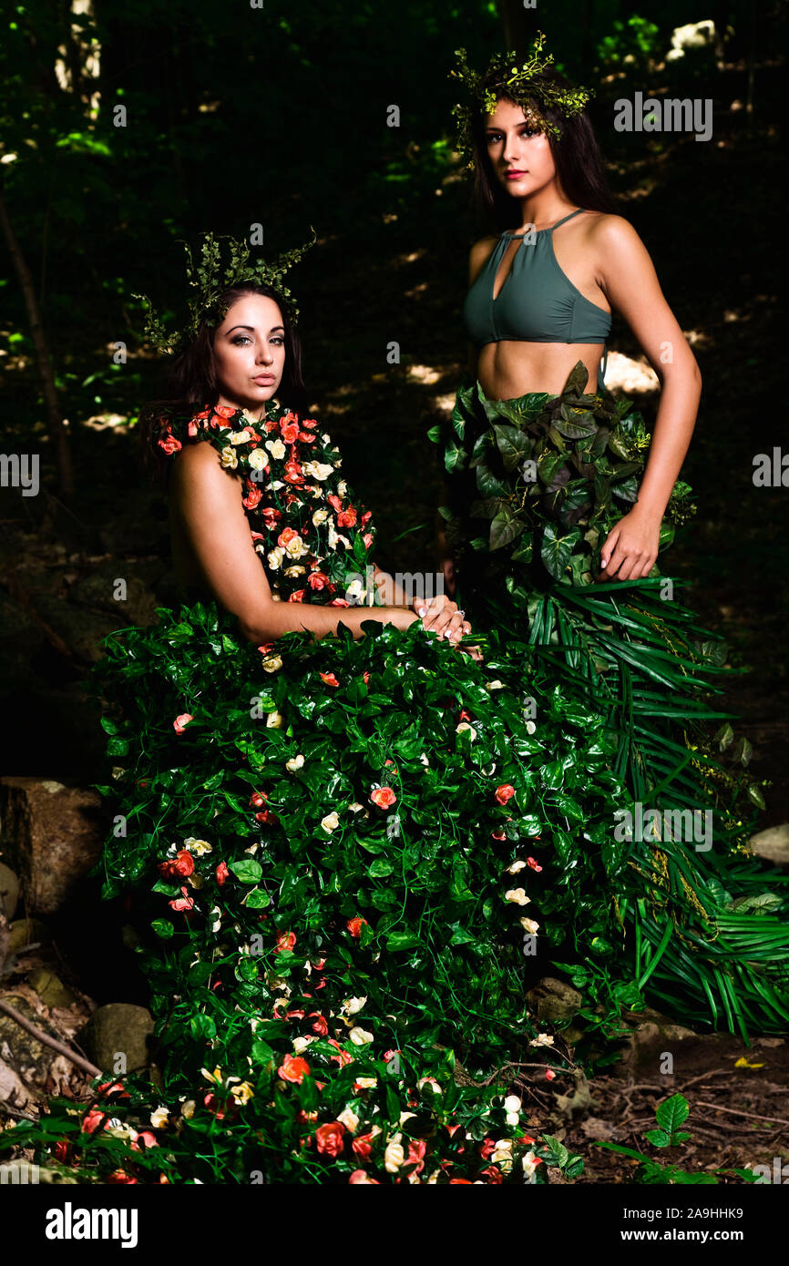 La haute couture en plein air de deux femmes 1 dans une robe de fleurs et de feuilles et l'autre dans une jupe de feuilles. Les deux ont en tête conçu sur mesure pièces Banque D'Images