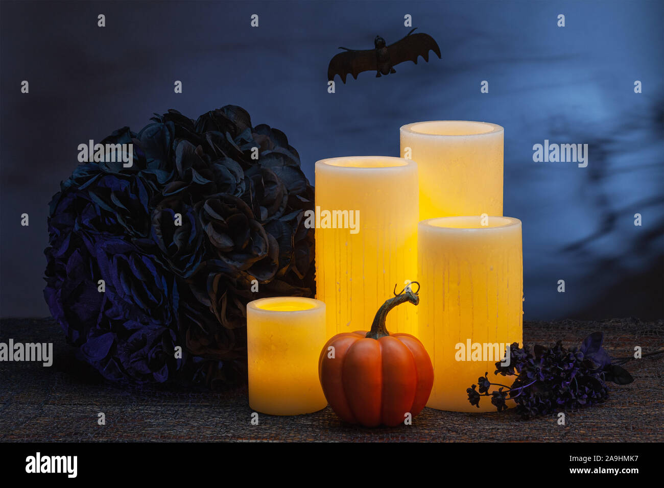 Halloween de vie encore de bougies en cire électrique jaune avec une petite citrouille, fleurs noir et d'un battant bat Banque D'Images