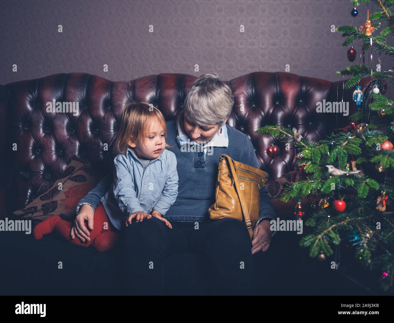 Un enfant et sa grand-mère sont assis sur un canapé près de l'arbre de Noël Banque D'Images