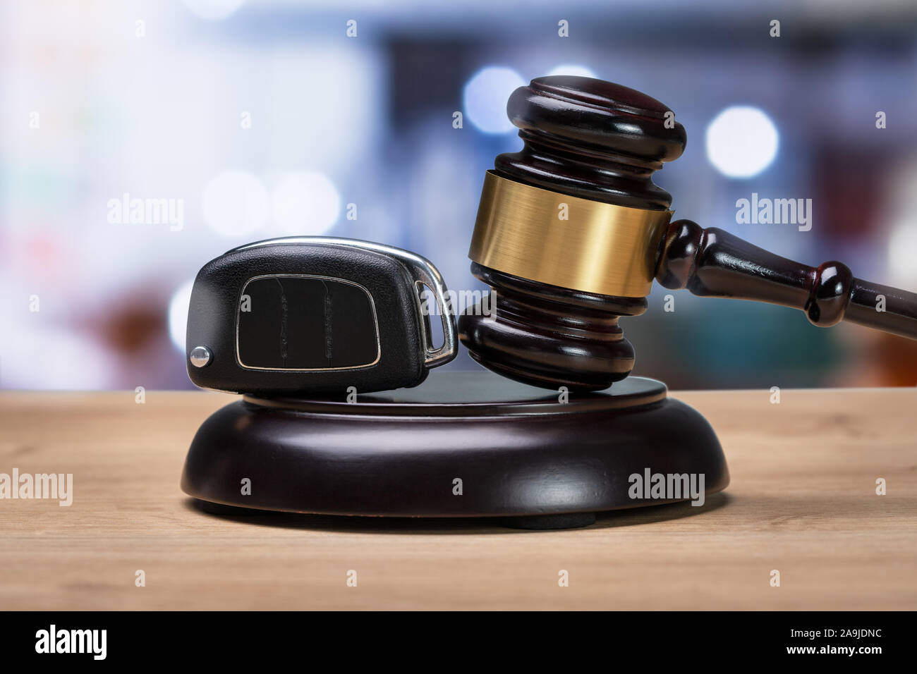 Close-up d'un marteau et clé de voiture sur le bloc de frappe plus de bureau en bois Banque D'Images