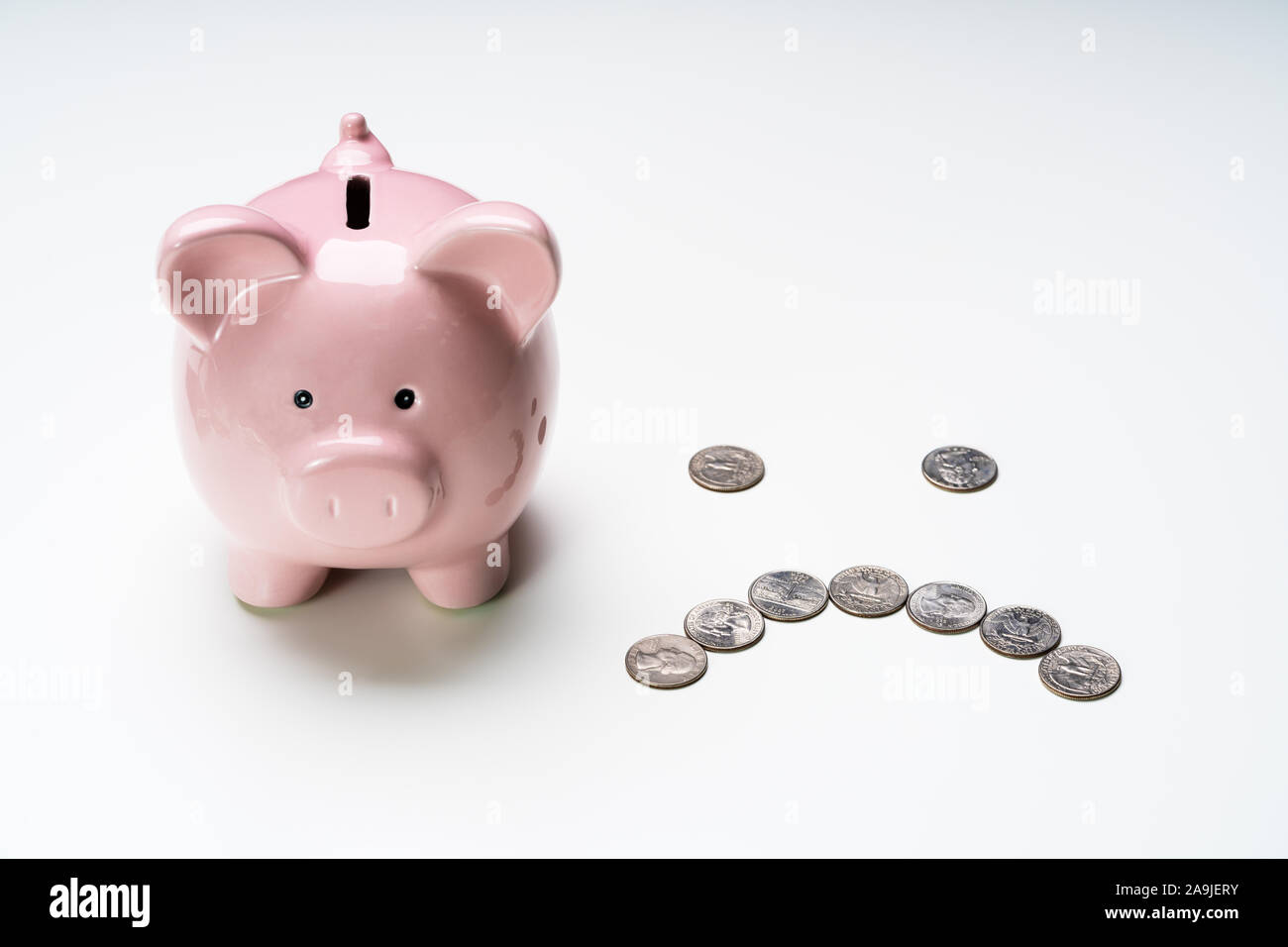 High Angle View Of Pink Piggy Bank près de coins sur la surface gris Banque D'Images