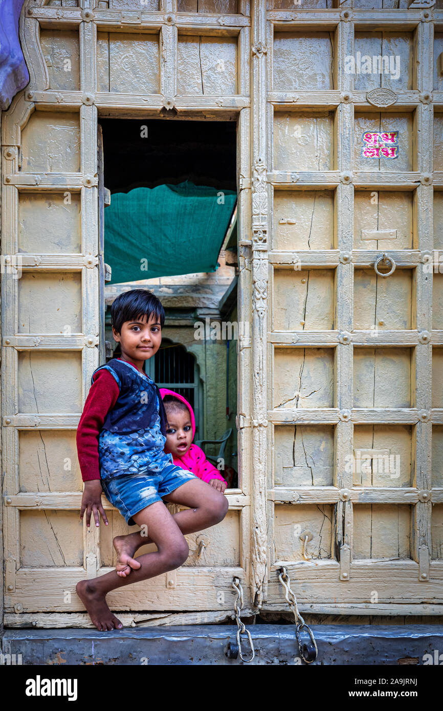 Deux enfants regardant hors d'une porte d'ouverture d'un ancien hablei, Jaisalmer, Rajasthan, Inde Banque D'Images