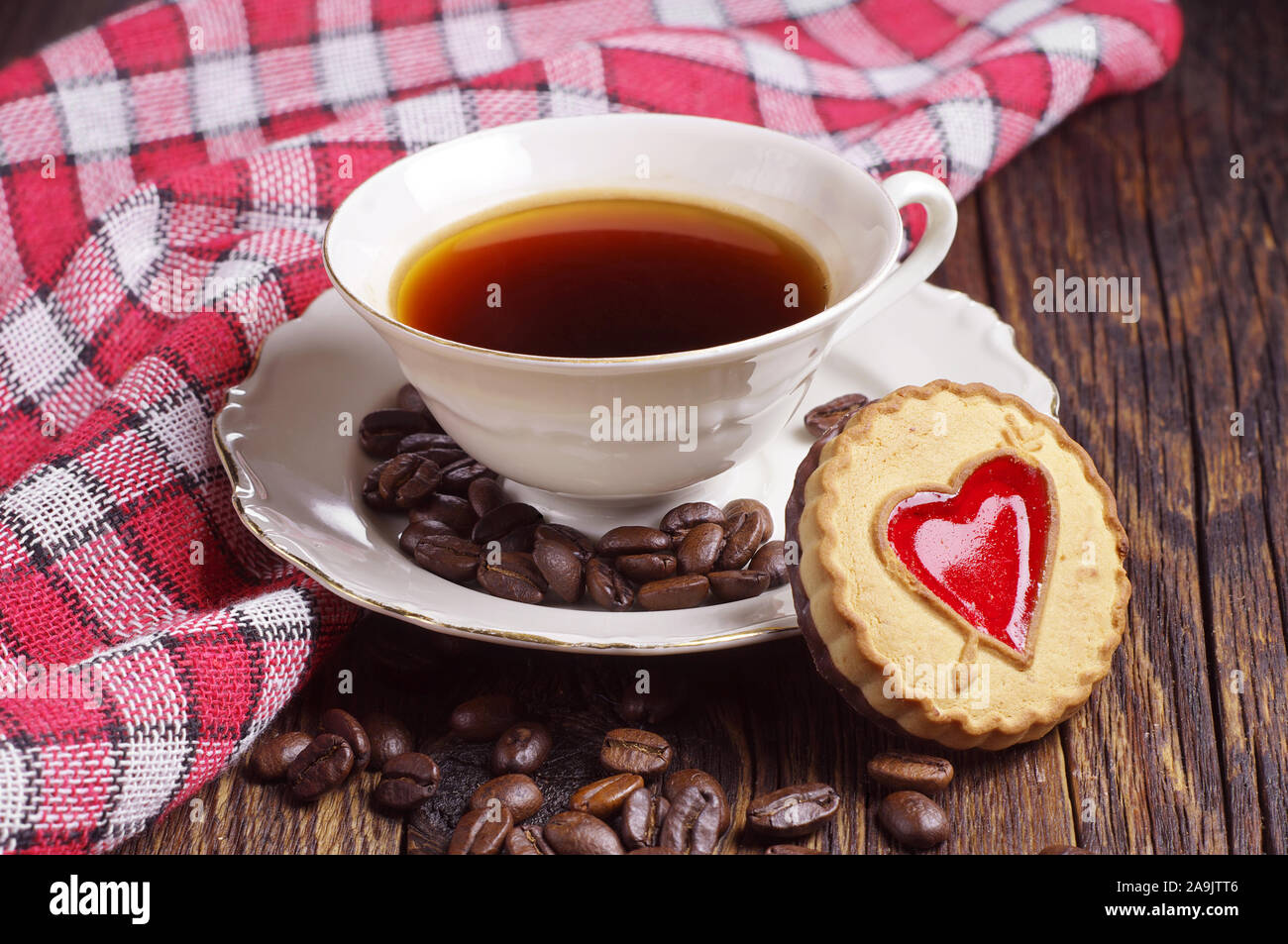 Tasse de café avec cookie sur table rustique covert nappe rouge Banque D'Images
