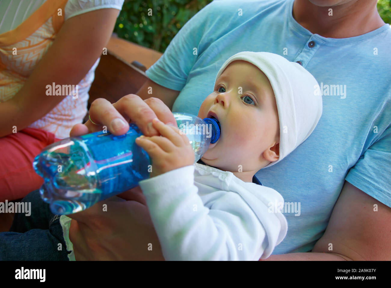 Un petit enfant est assis et des boissons de l'eau d'une bouteille. Banque D'Images