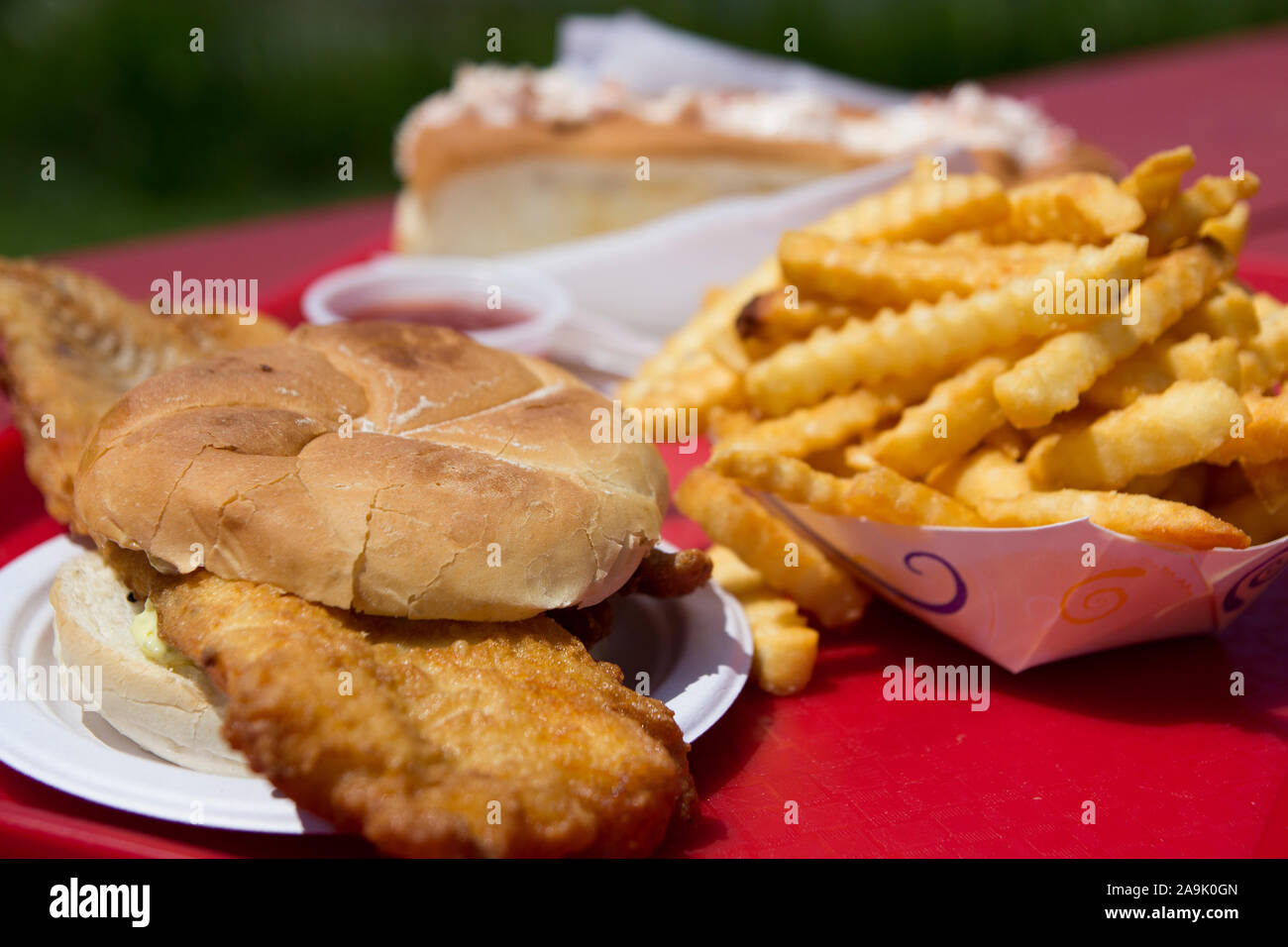 Produit alimentaire Gros plan sur une friture de poissons sur un petit pain sandwich, frites et un rouleau de homard, servi sur un plateau en plastique rouge à l'extérieur. Dans le Maine, États-Unis Banque D'Images