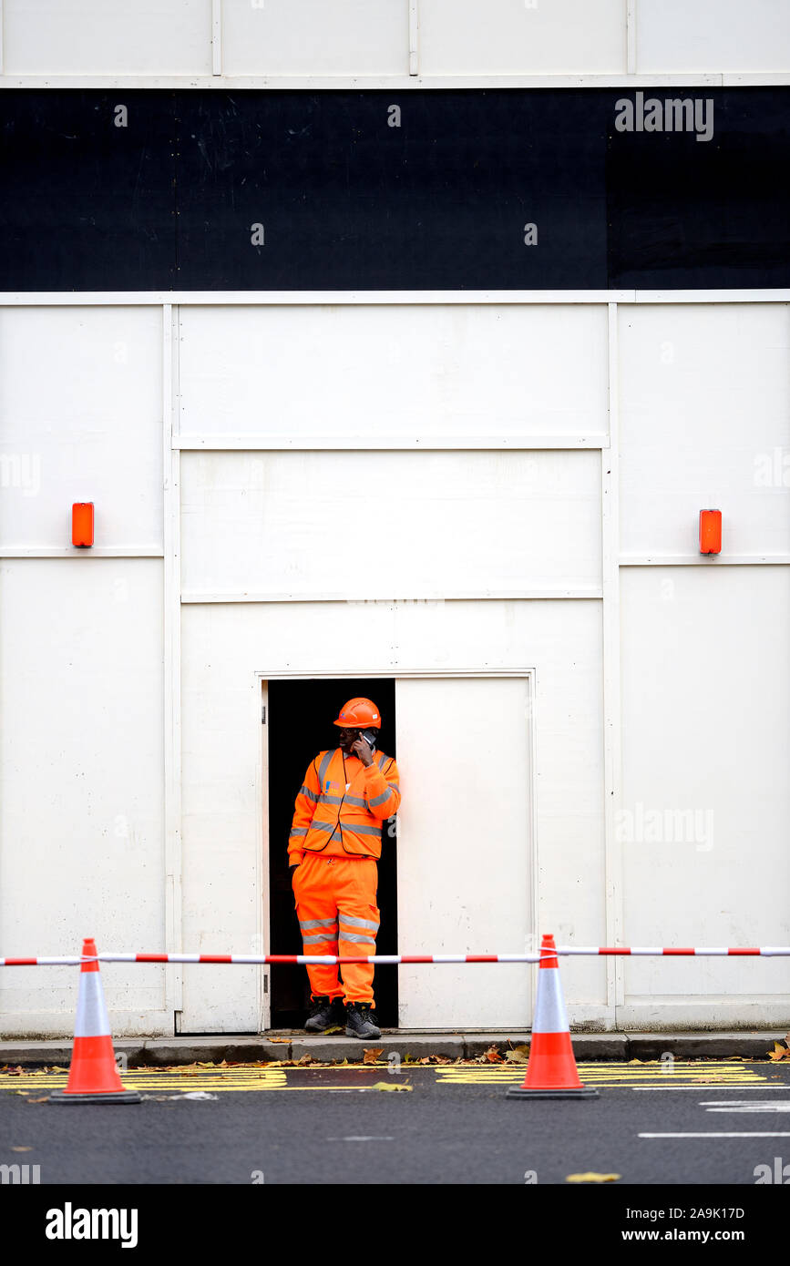 Londres, Angleterre, Royaume-Uni. Travailleur en bleu de travail haute visibilité sur son téléphone mobile, Whitehall Banque D'Images