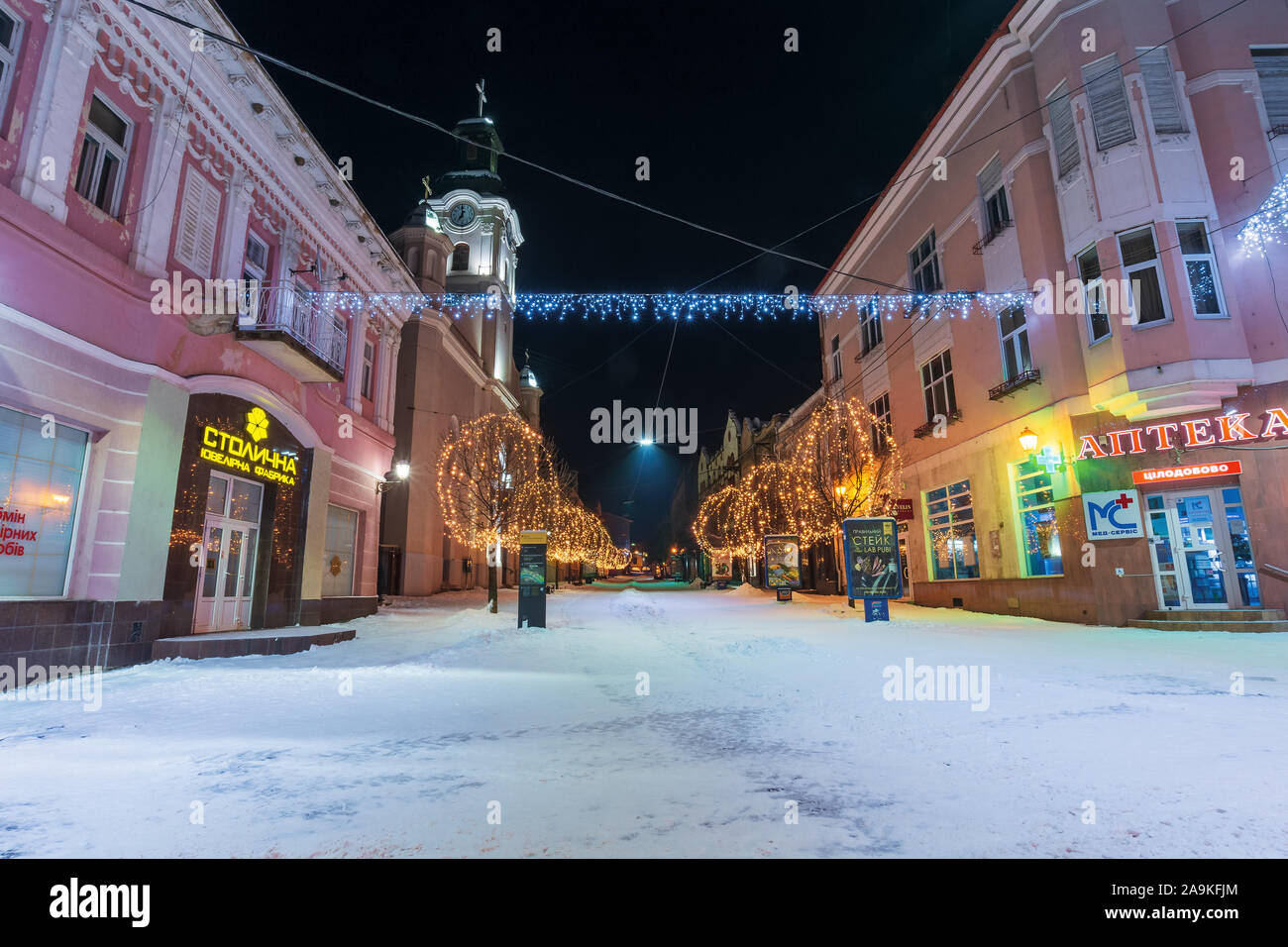 Uzhgorod, Ukraine - 06 jan 2019 : nuit d'hiver en ville. superbe illumination de noël bleu et jaune vide. Voloshyna street couvertes de neige. cath Banque D'Images