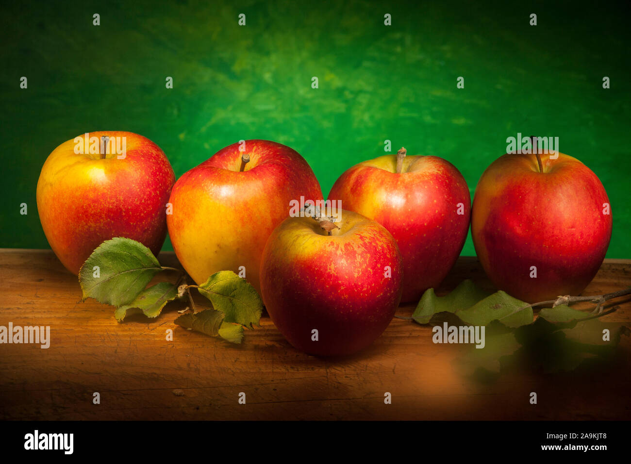 Composition pommes sur table en bois avec fond flou vert faites à la lumière de la technique de la brosse Banque D'Images