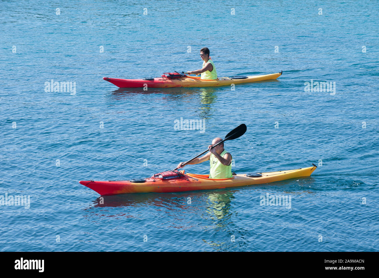 Deux hommes pagayer en kayak le long de la côte de la mer Banque D'Images