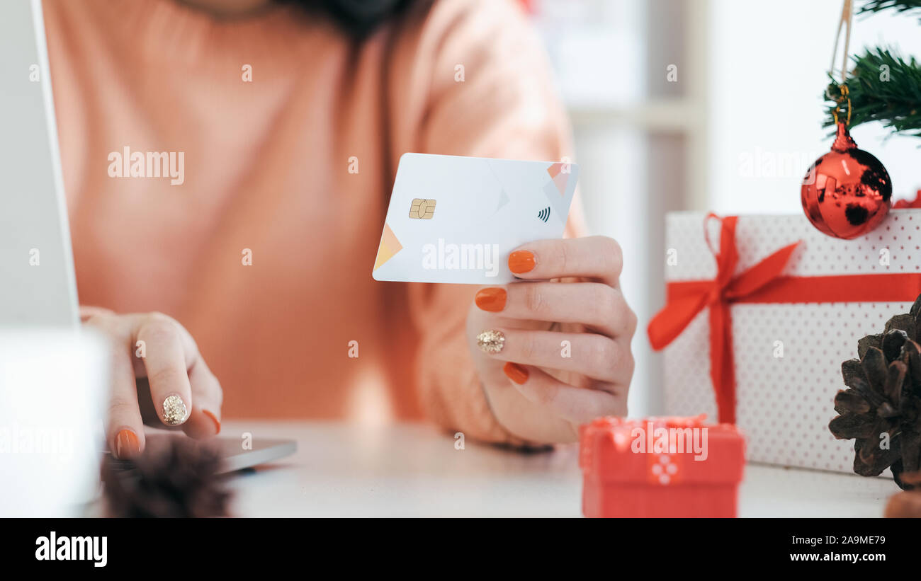 Jeune femme tenant une carte de crédit et faisant des achats en ligne. Nouvel an, shopping de cadeaux de noël. Banque D'Images