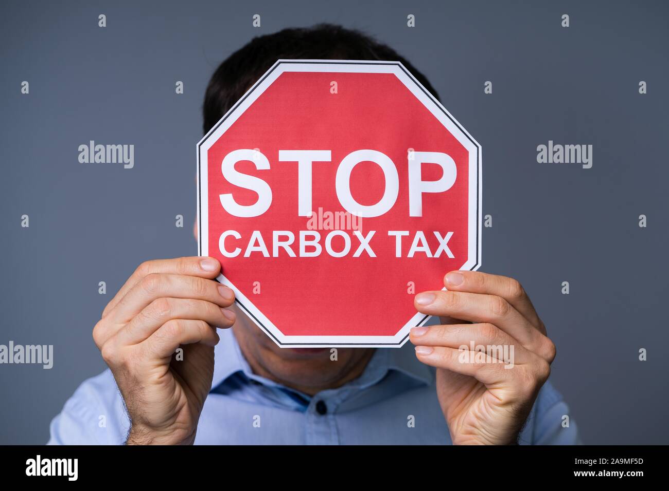 L'homme se cachant son visage derrière Arrêter panneau rouge avec taxe carbone Texte sur fond gris Banque D'Images